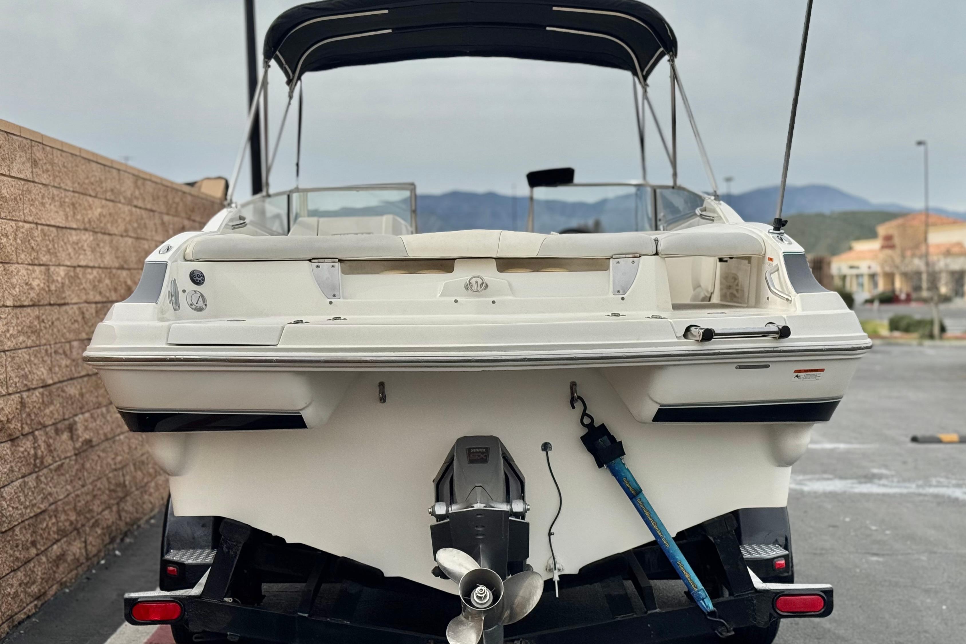 2006 Larson LXi 248 boat, rear view, parked outdoors with mountains in background.