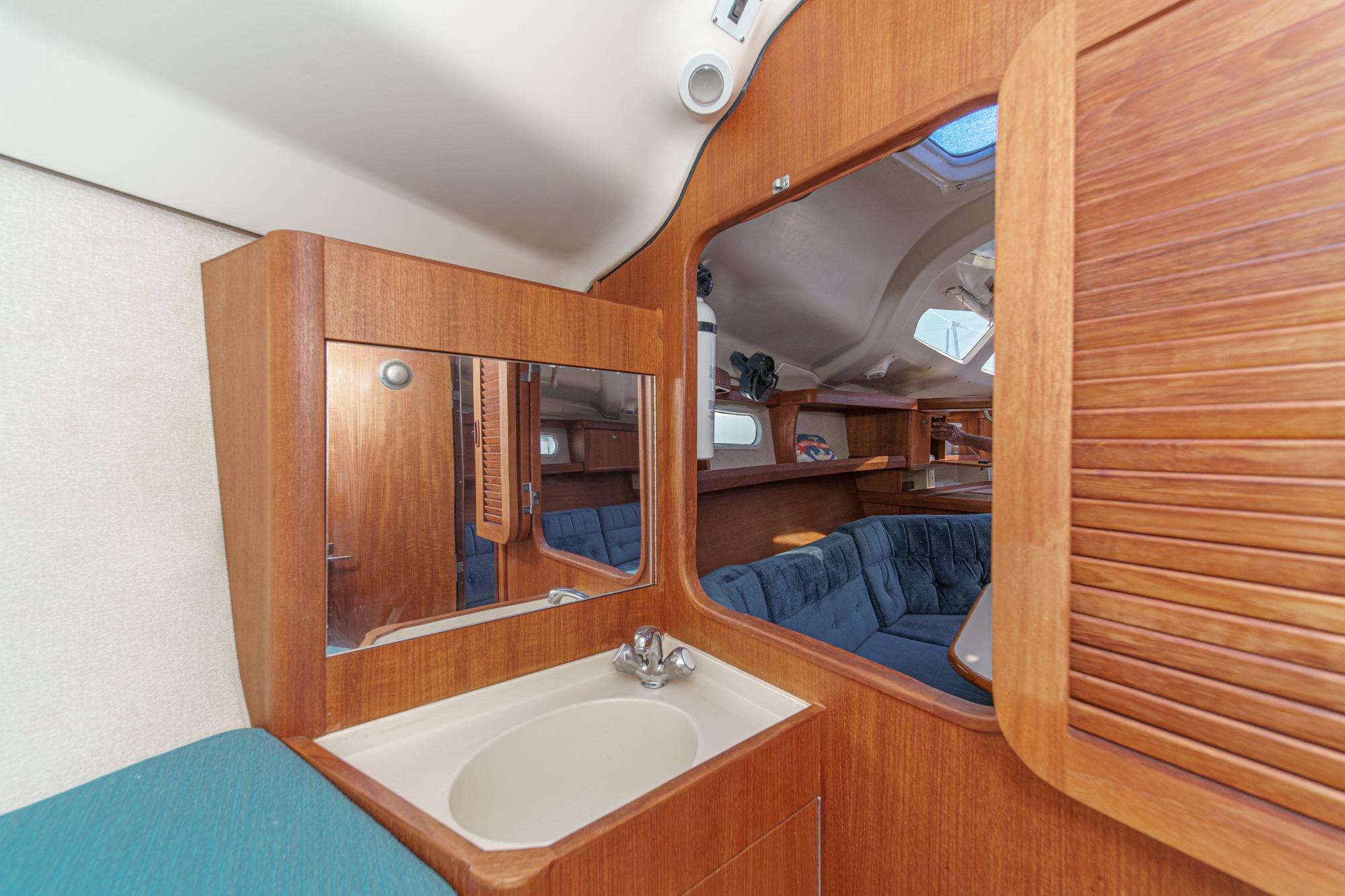 Interior of a 1996 Hunter 376 sailboat featuring a wooden vanity and cozy seating area.