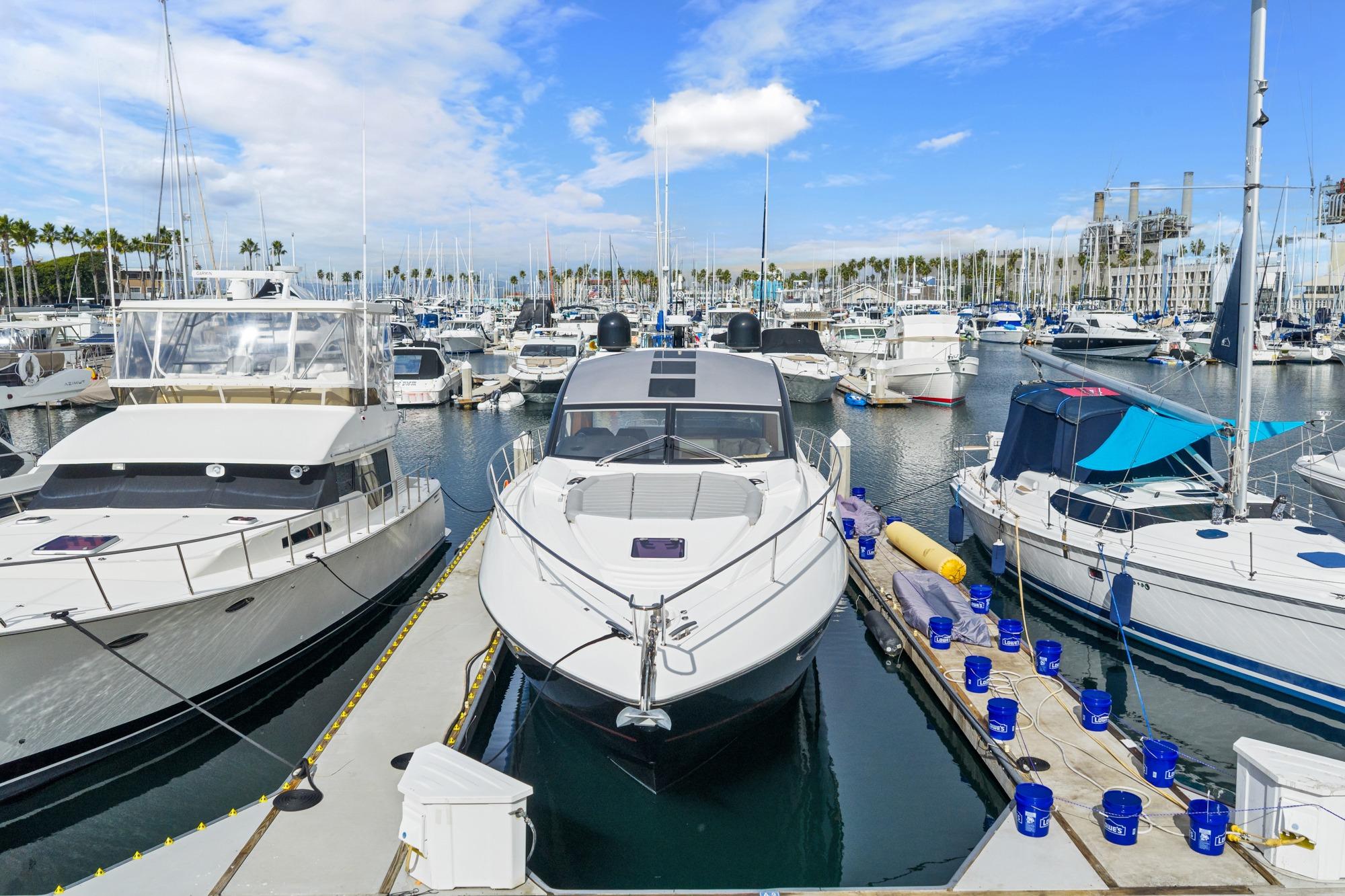 2019 Sunseeker Predator 57 yacht docked in a busy marina under a clear blue sky.