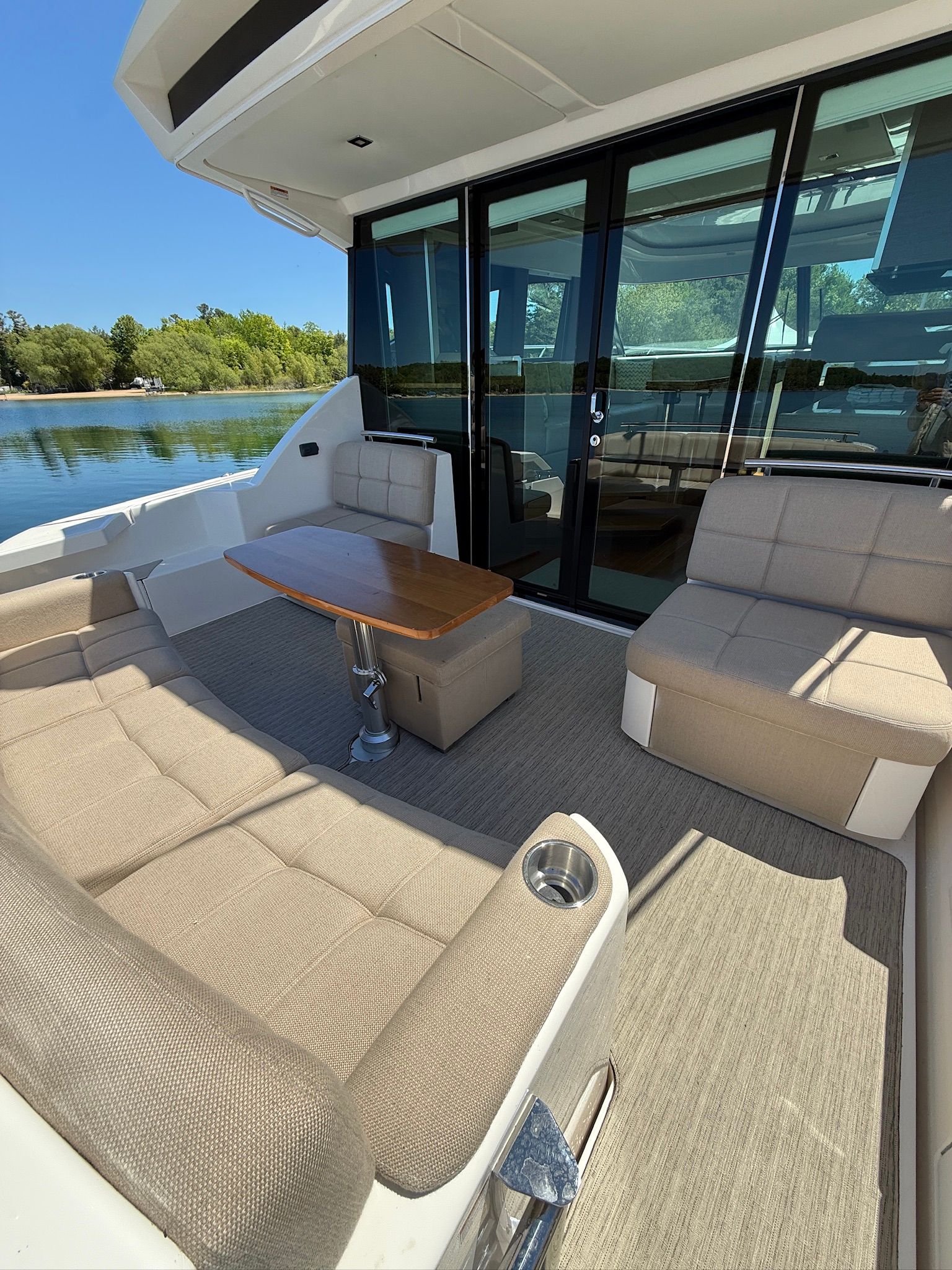 The image shows the cockpit of a 2017 Tiara Yachts C44 Coupe with beige upholstery and a wooden table.