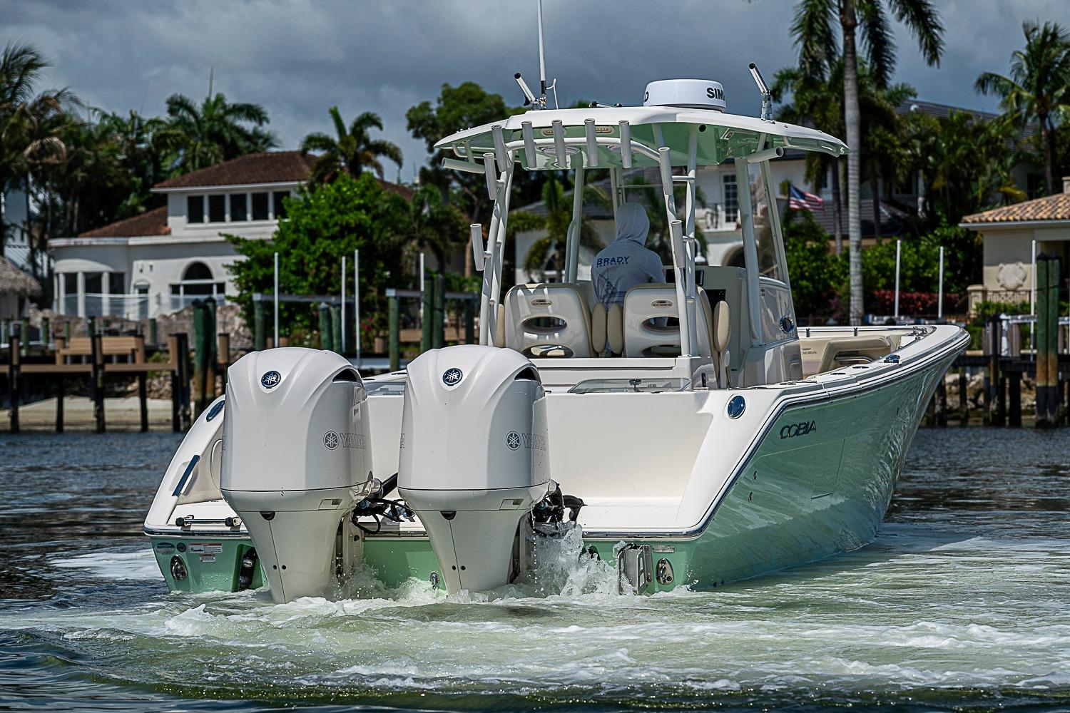 2019 Cobia 320 Center Console boat with dual engines on a scenic waterway.