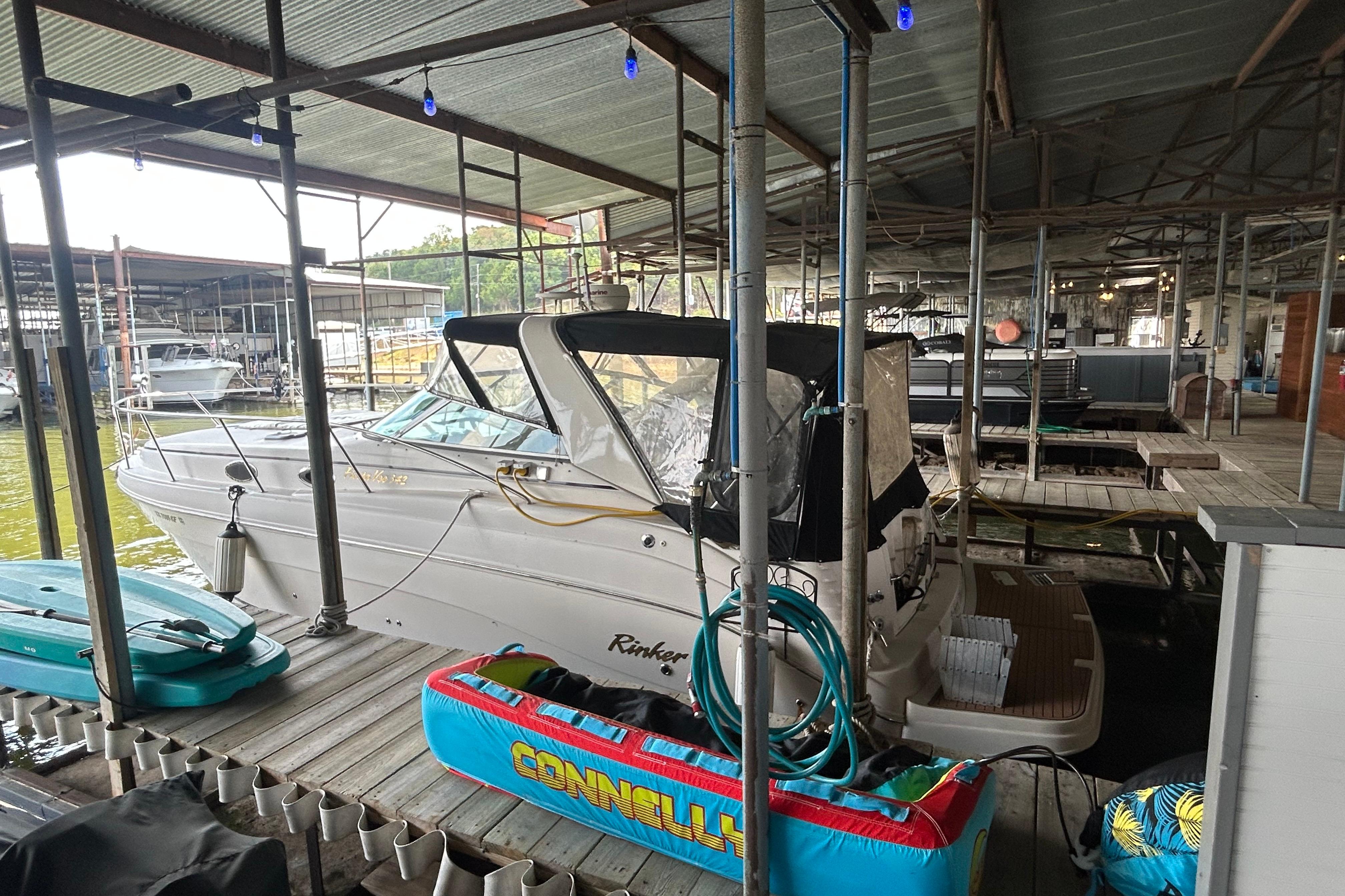 2003 Rinker 342 Express Cruiser docked in a covered marina with water sports equipment.