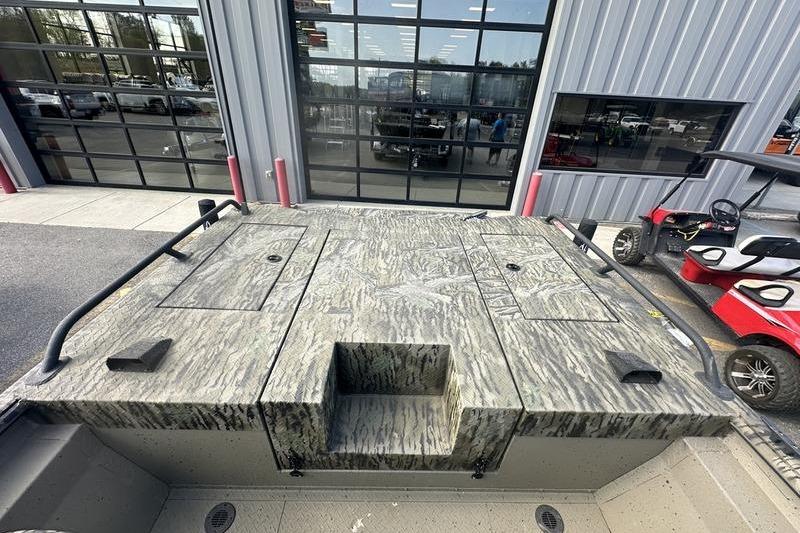 2025 SeaArk Predator 300 AK boat with camo deck, parked near a garage.