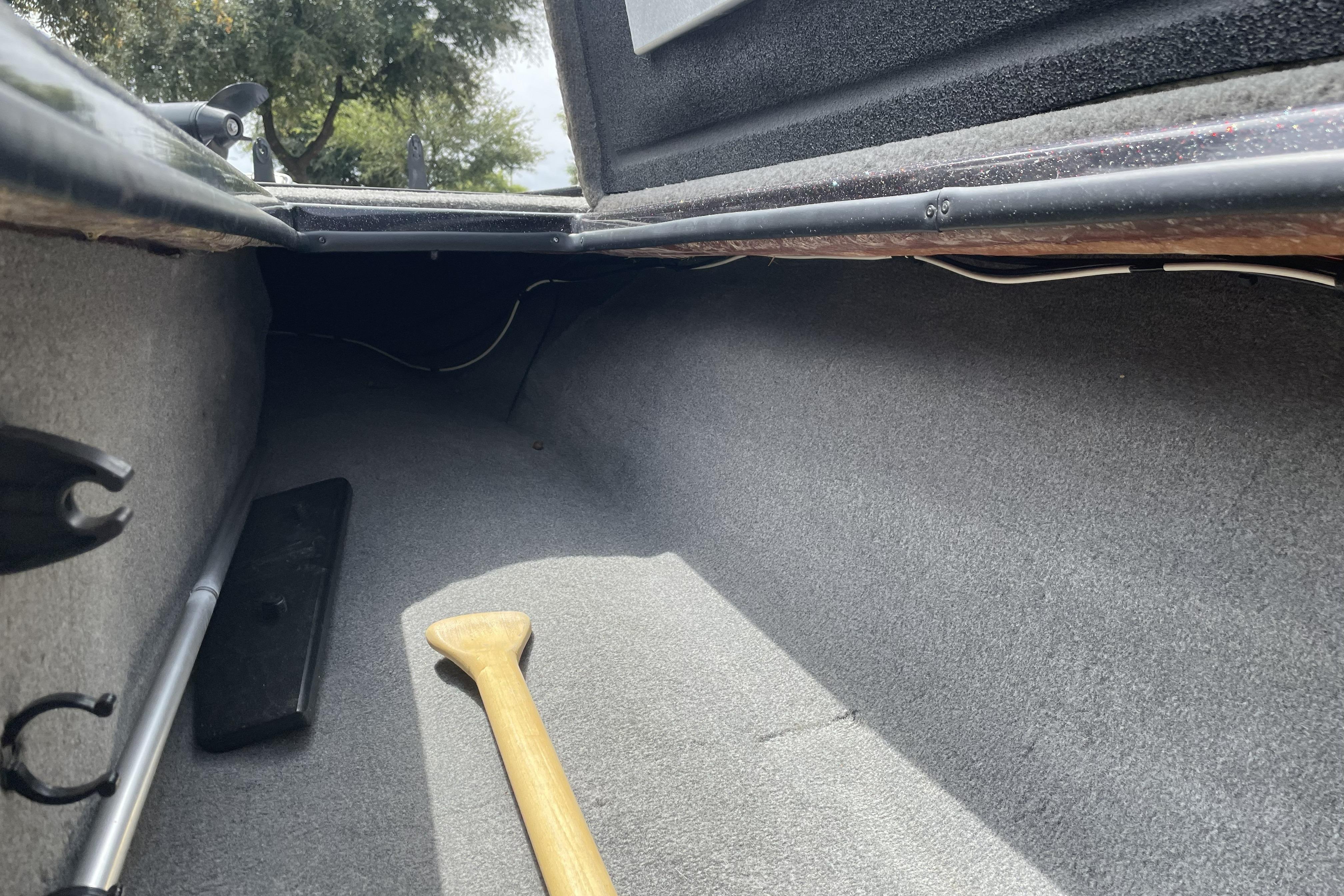Interior view of a 2013 Nitro Z-8 boat storage compartment with a wooden paddle.