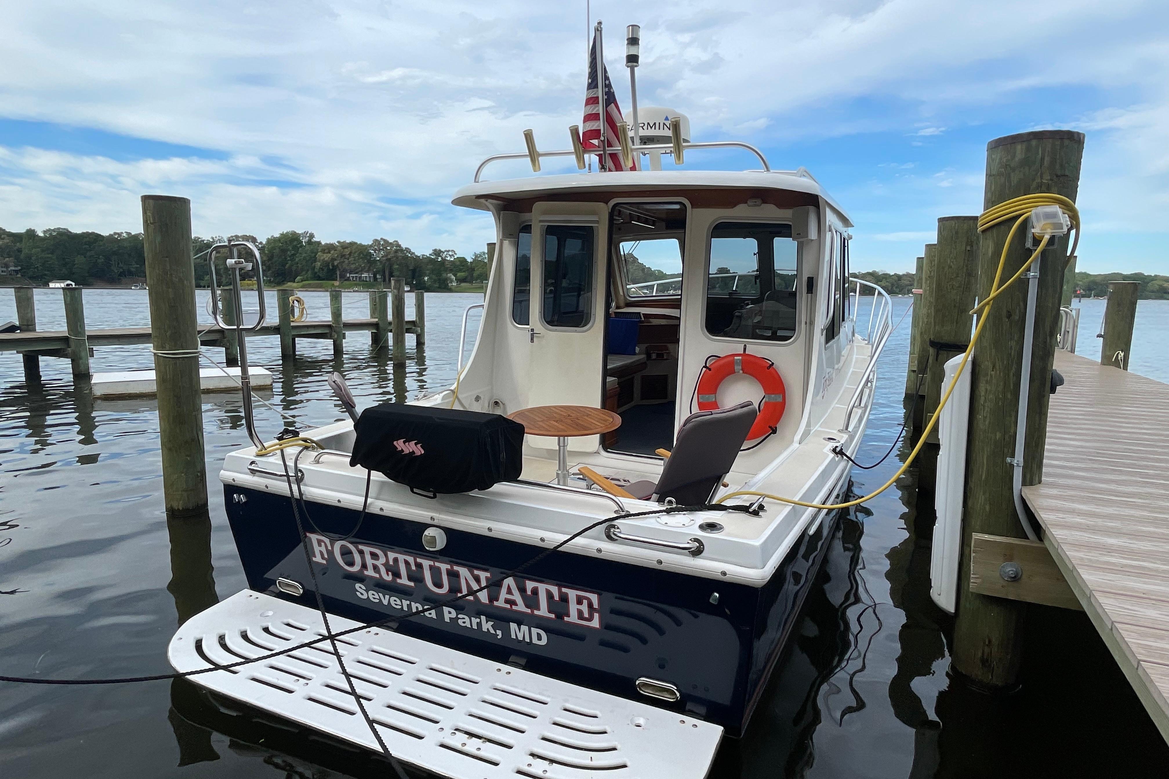 Fox Island Thirty Sedan Cruiser 2005 docked, featuring a spacious deck and serene waterfront view.