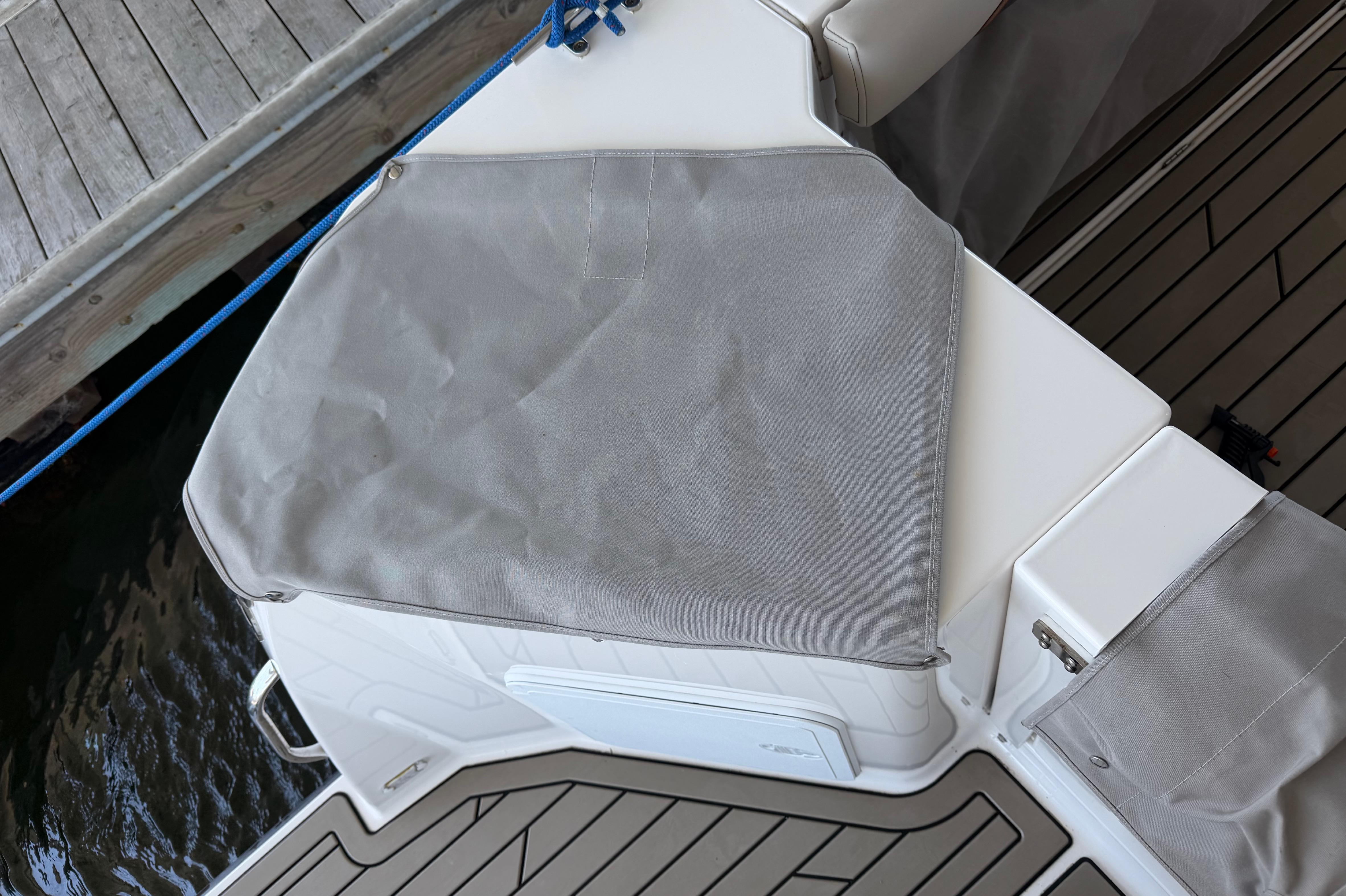 2023 Cutwater C-288 Coupe boat deck with protective cover, docked by wooden pier.