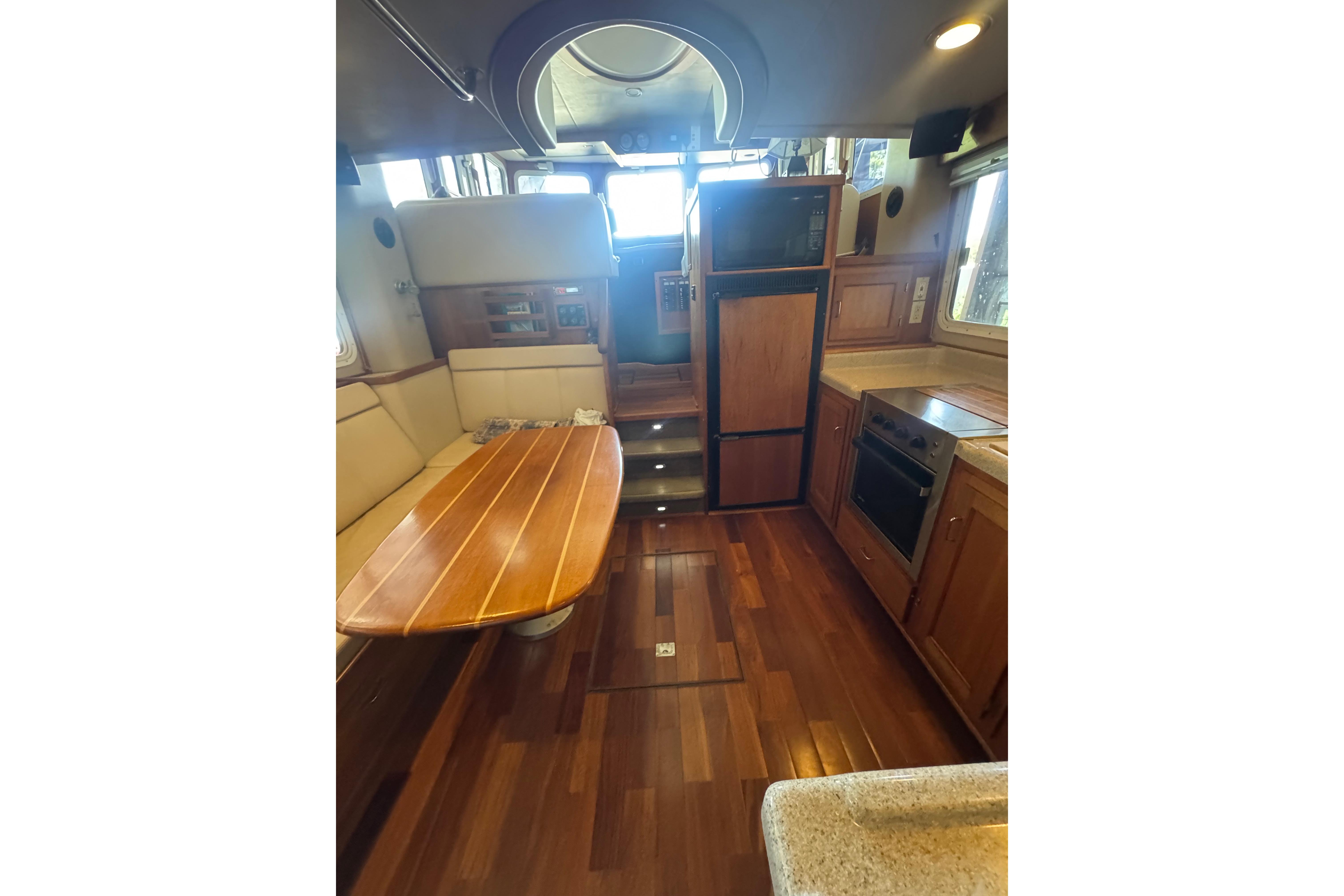 Interior of 2005 American Tug 34, featuring wood flooring, dining area, and kitchen appliances.