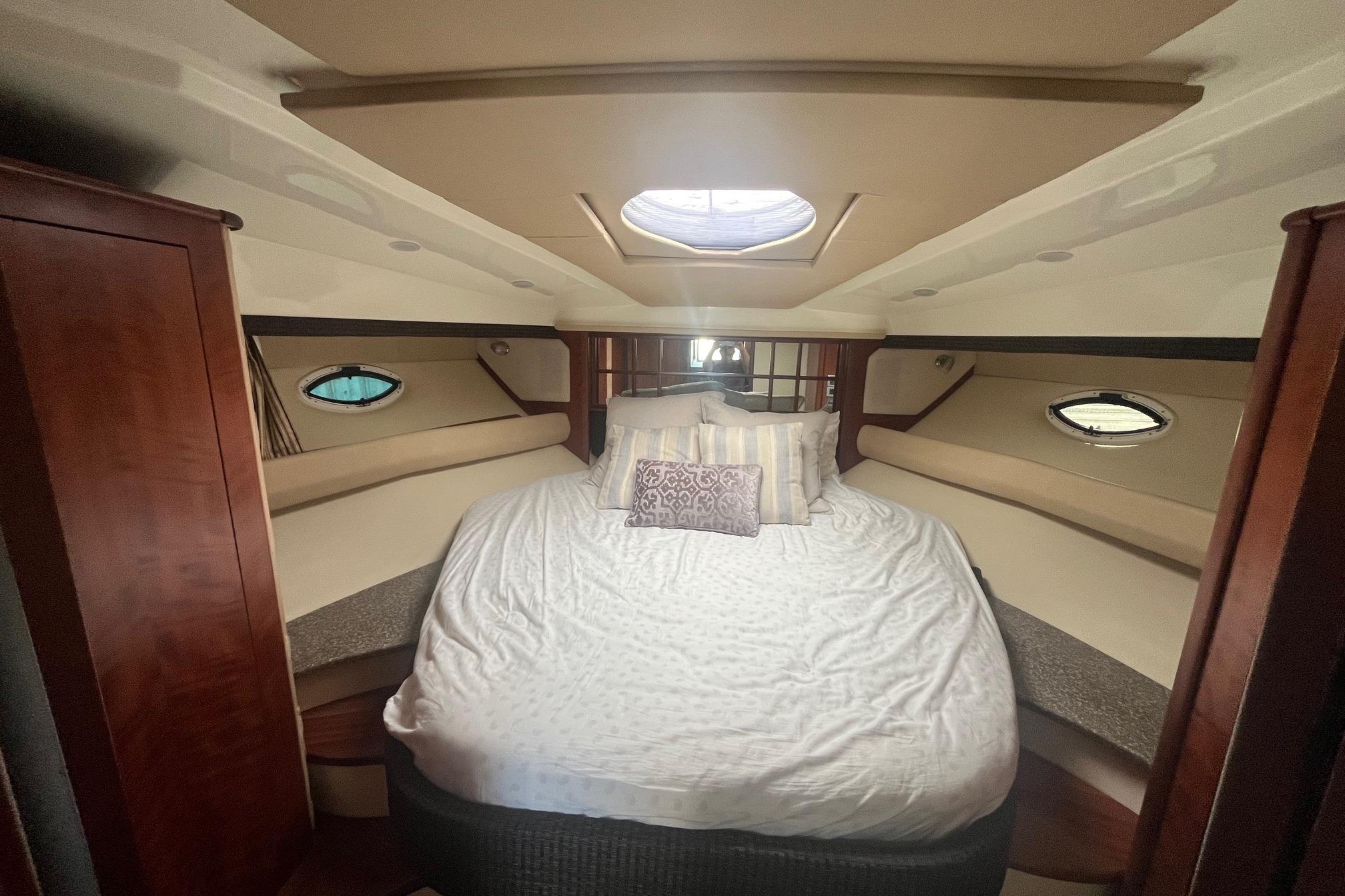 Luxurious cabin interior of 2010 Monterey 400 Sport Yacht with cozy bed and porthole windows.