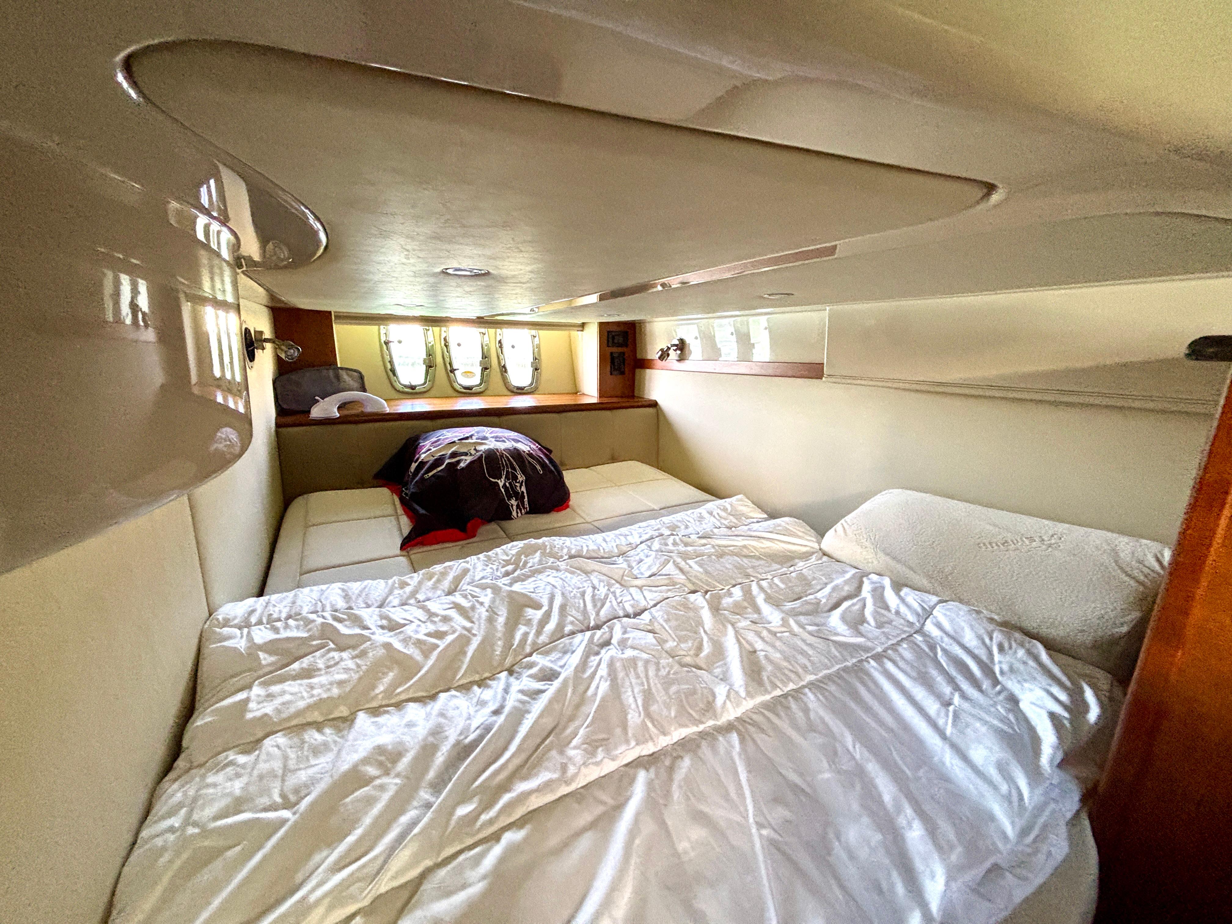 Interior cabin of 2007 Cruisers Yachts 447 Sport Sedan with cozy bed and porthole windows.