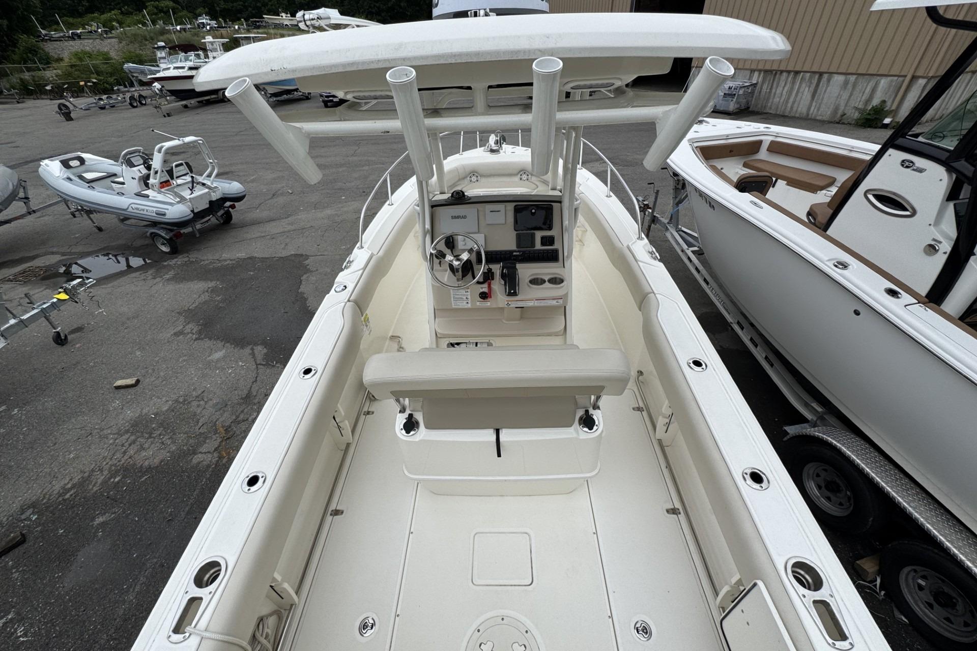 2024 Boston Whaler 230 Outrage boat interior with helm and seating, docked outdoors.