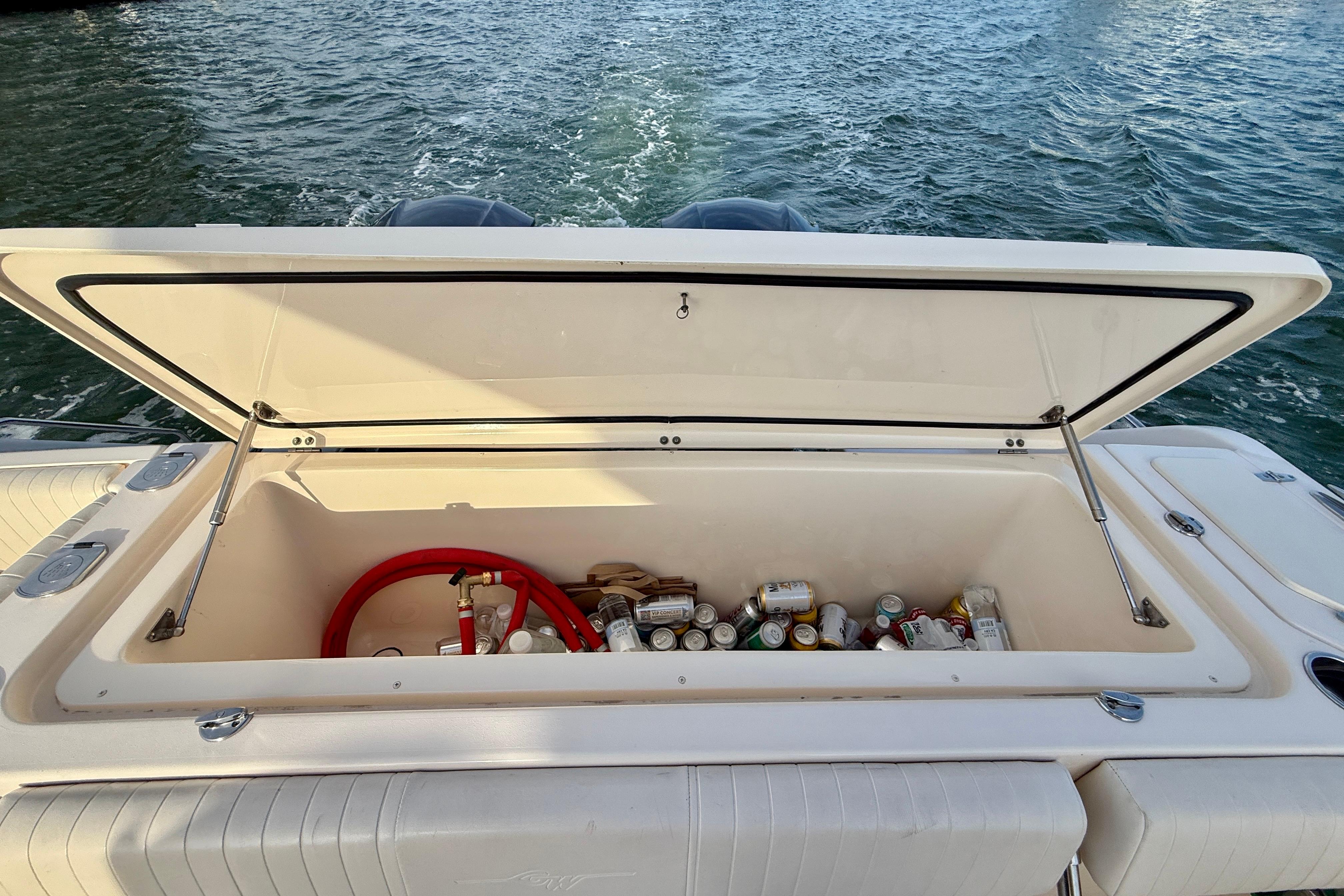 Open storage compartment on 2012 Grady-White Canyon 336 boat, filled with drinks and supplies.