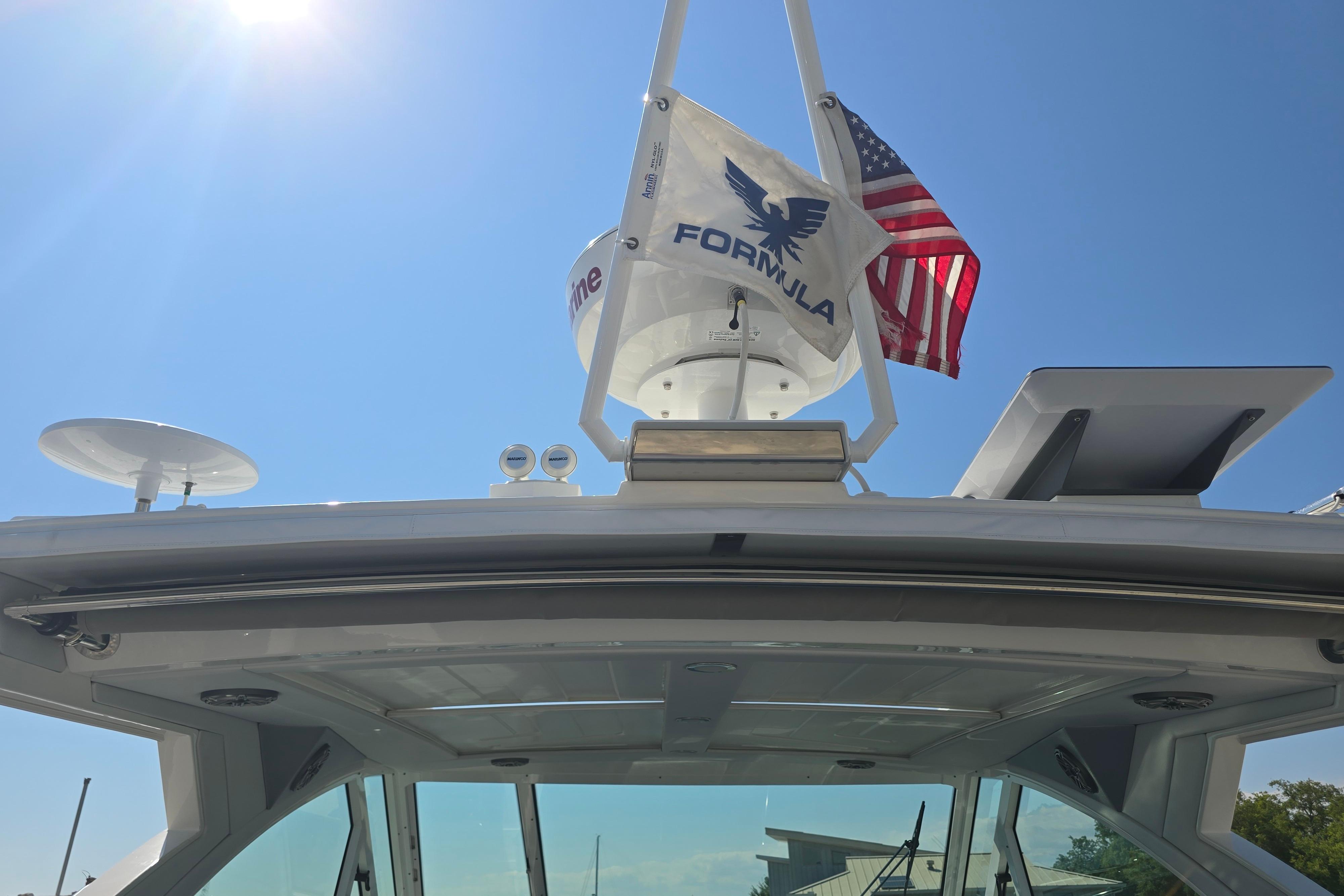 2025 Formula 380 Super Sport Crossover OB boat with flags under clear blue sky.