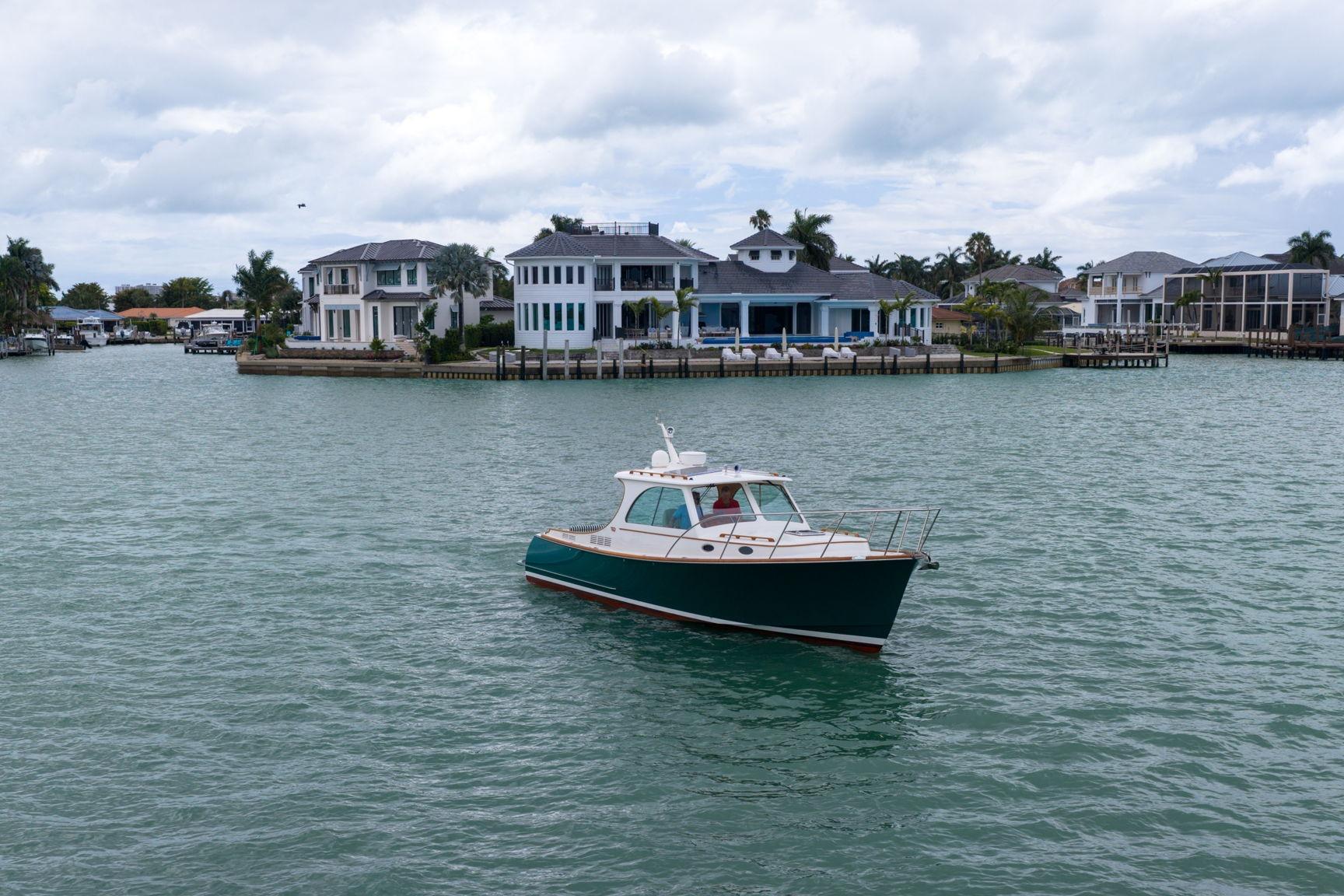 2013 Hinckley Picnic Boat 37 MKIII cruising near waterfront homes.