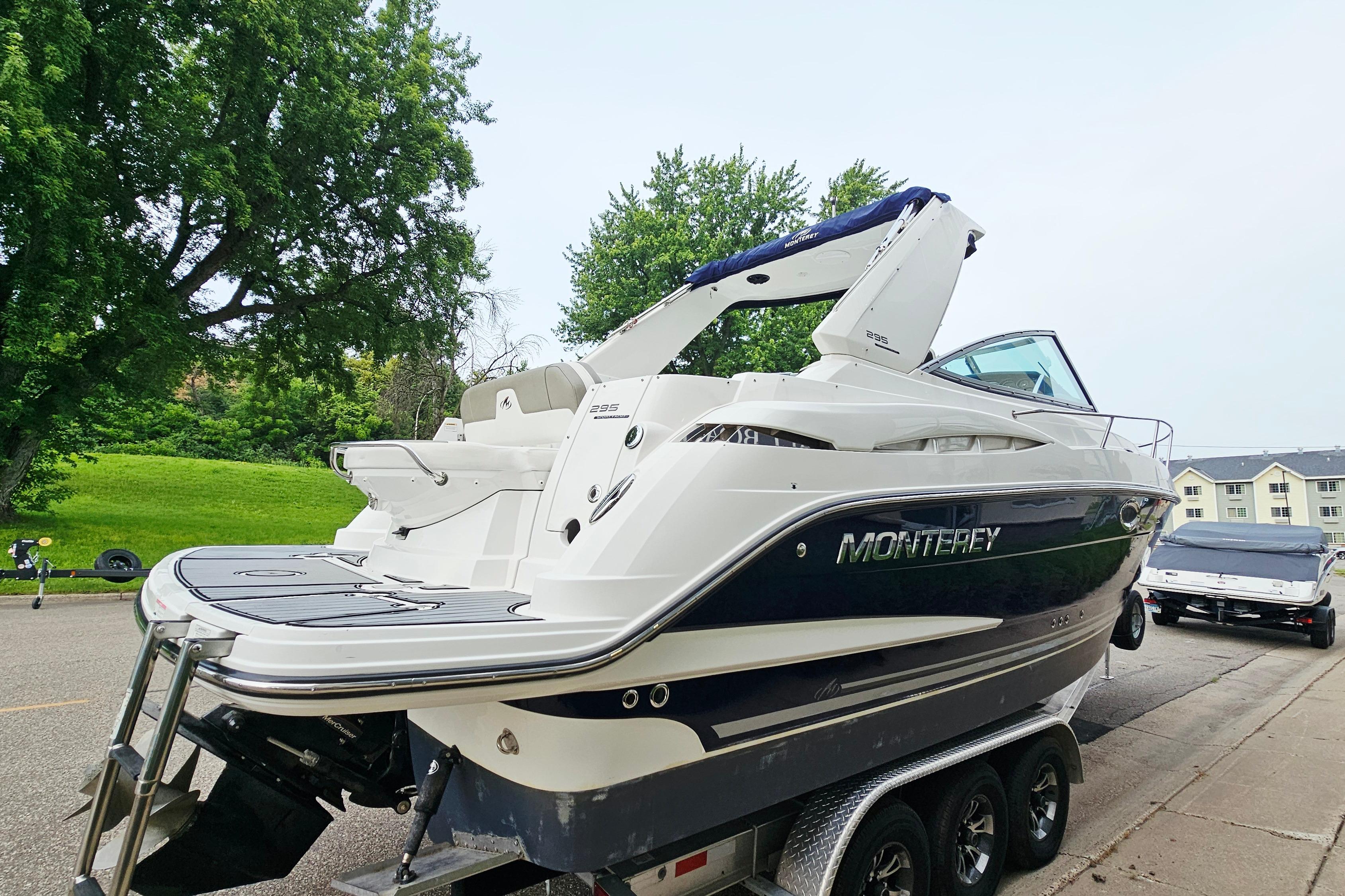 2016 Monterey 295 Sport Yacht on trailer, parked near lush greenery and residential area.