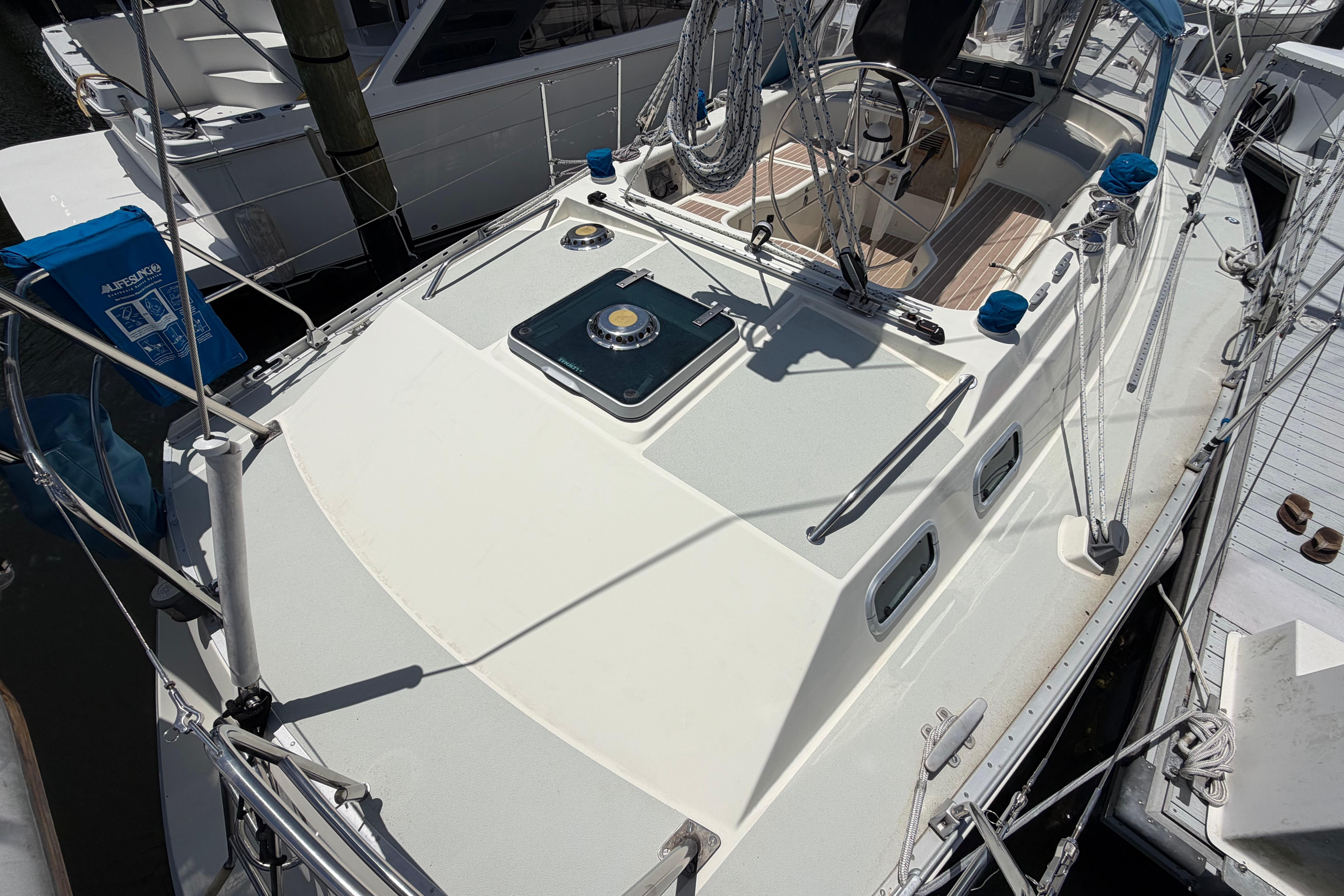 1987 Moody 376 sailboat deck with steering wheel and rigging, docked at marina.