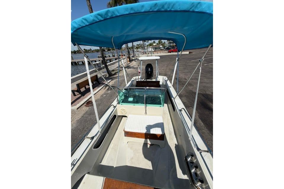1990 Boston Whaler 17 Newport boat with blue canopy, docked near waterfront.