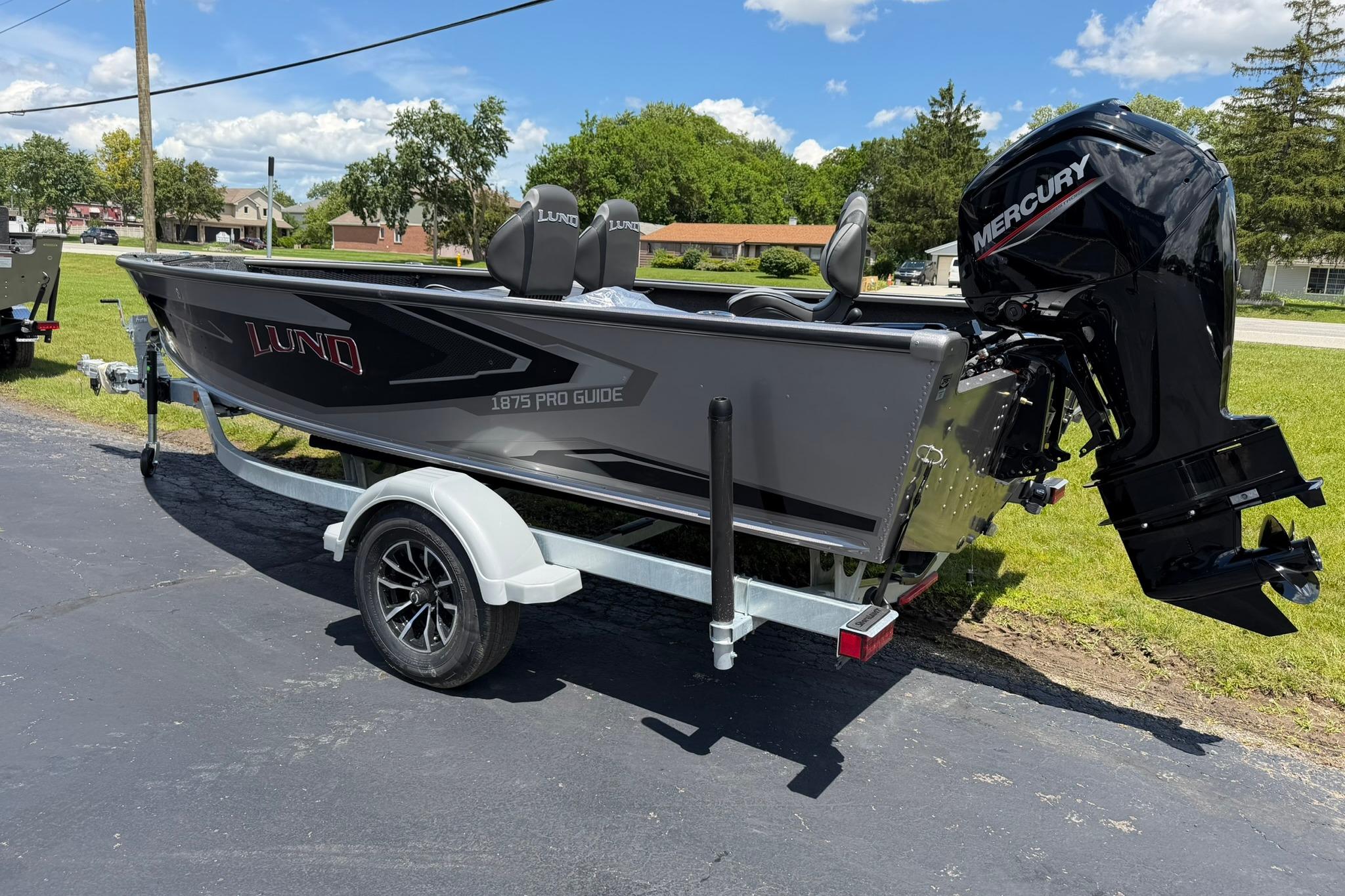 2027 Lund 1875 Pro Guide boat with Mercury engine on trailer, parked outdoors.