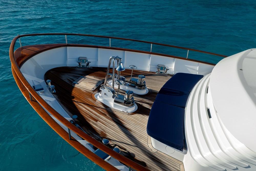 Luxury yacht deck with wooden finish, Royal Hakvoort Shipyard Canoe Stern, 2002 model, on blue water.
