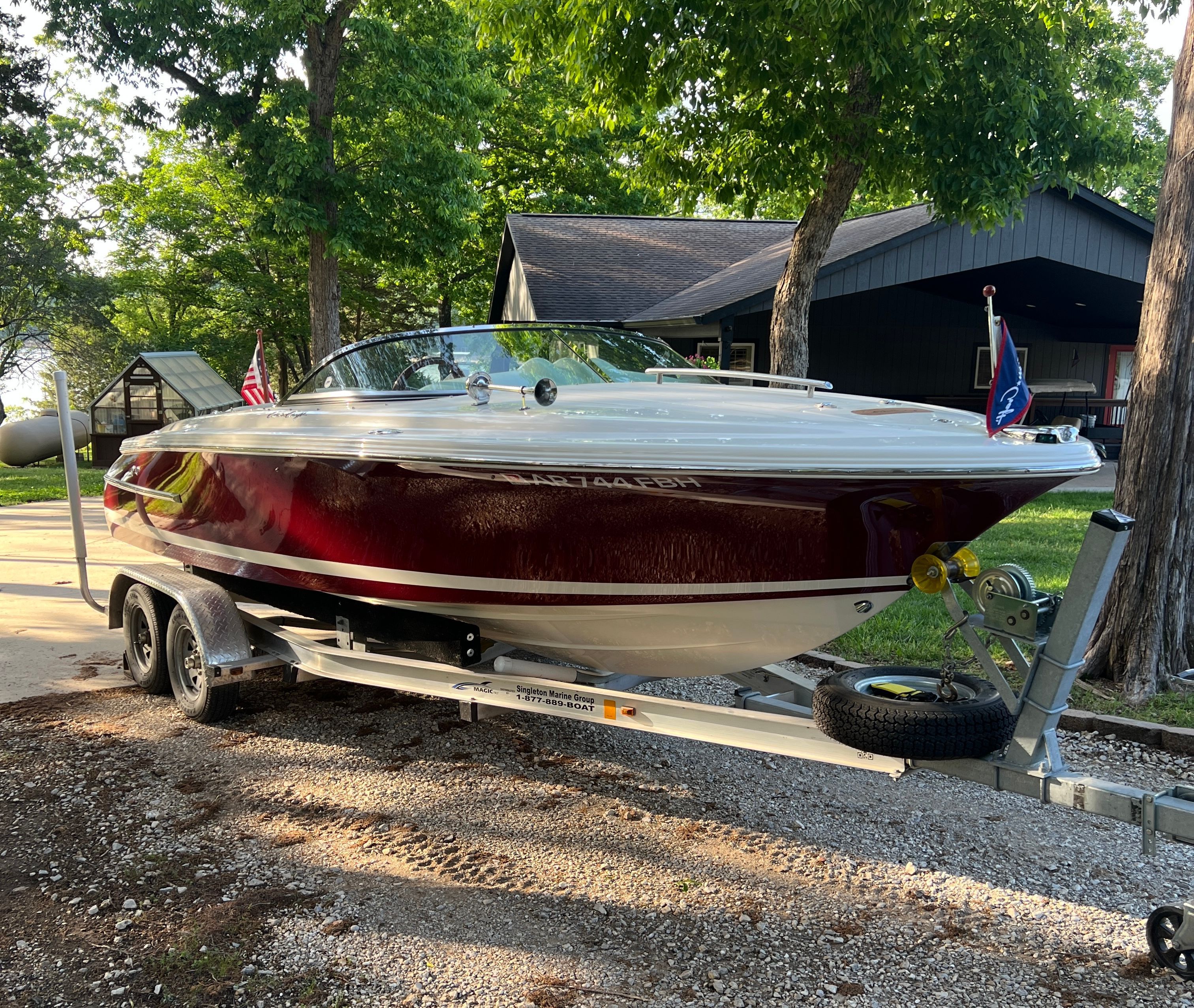 A 2006 Chris-Craft Speedster 20 on a trailer in front of a house.