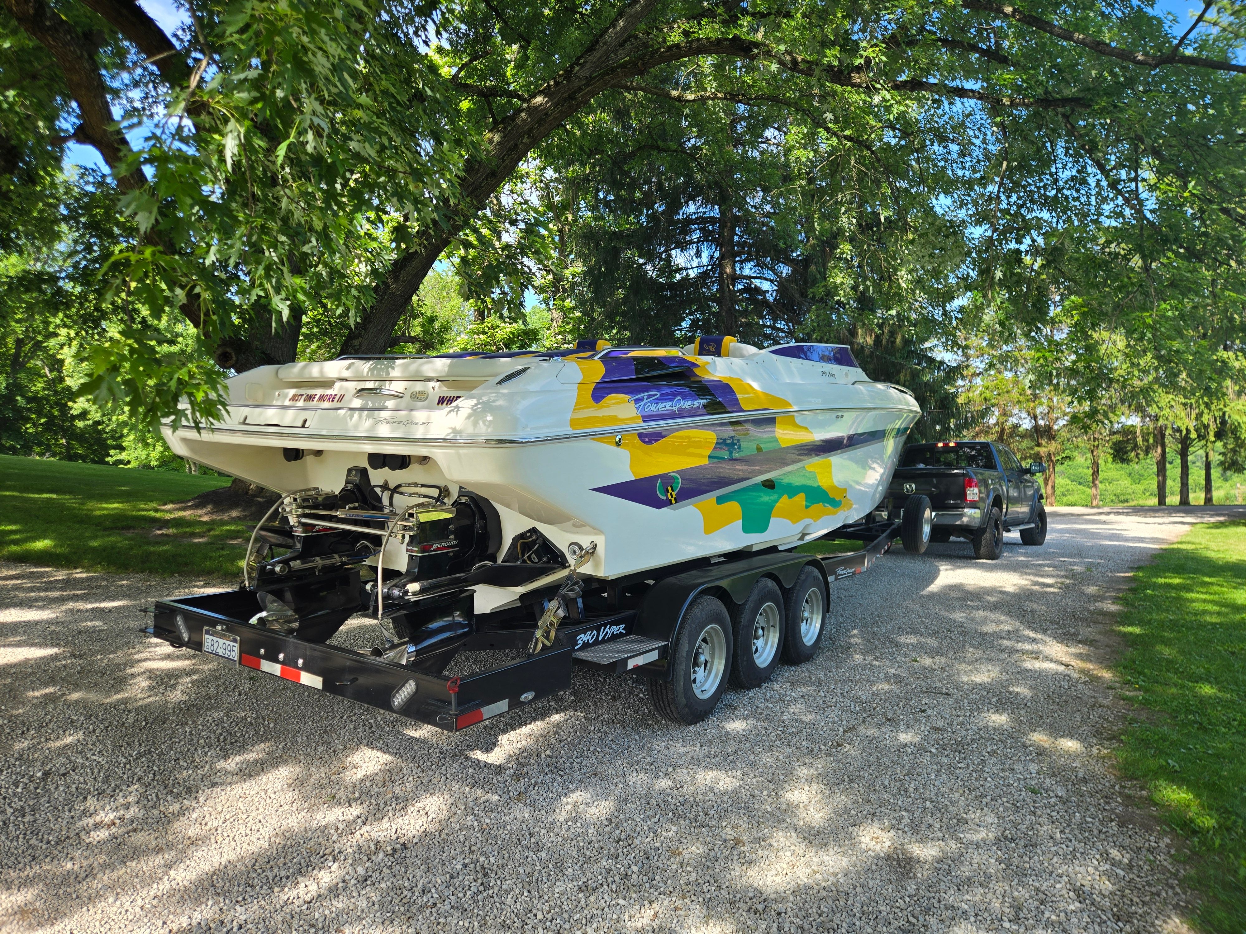A Powerquest 340 Vyper boat on a trailer, surrounded by trees on a gravel path.