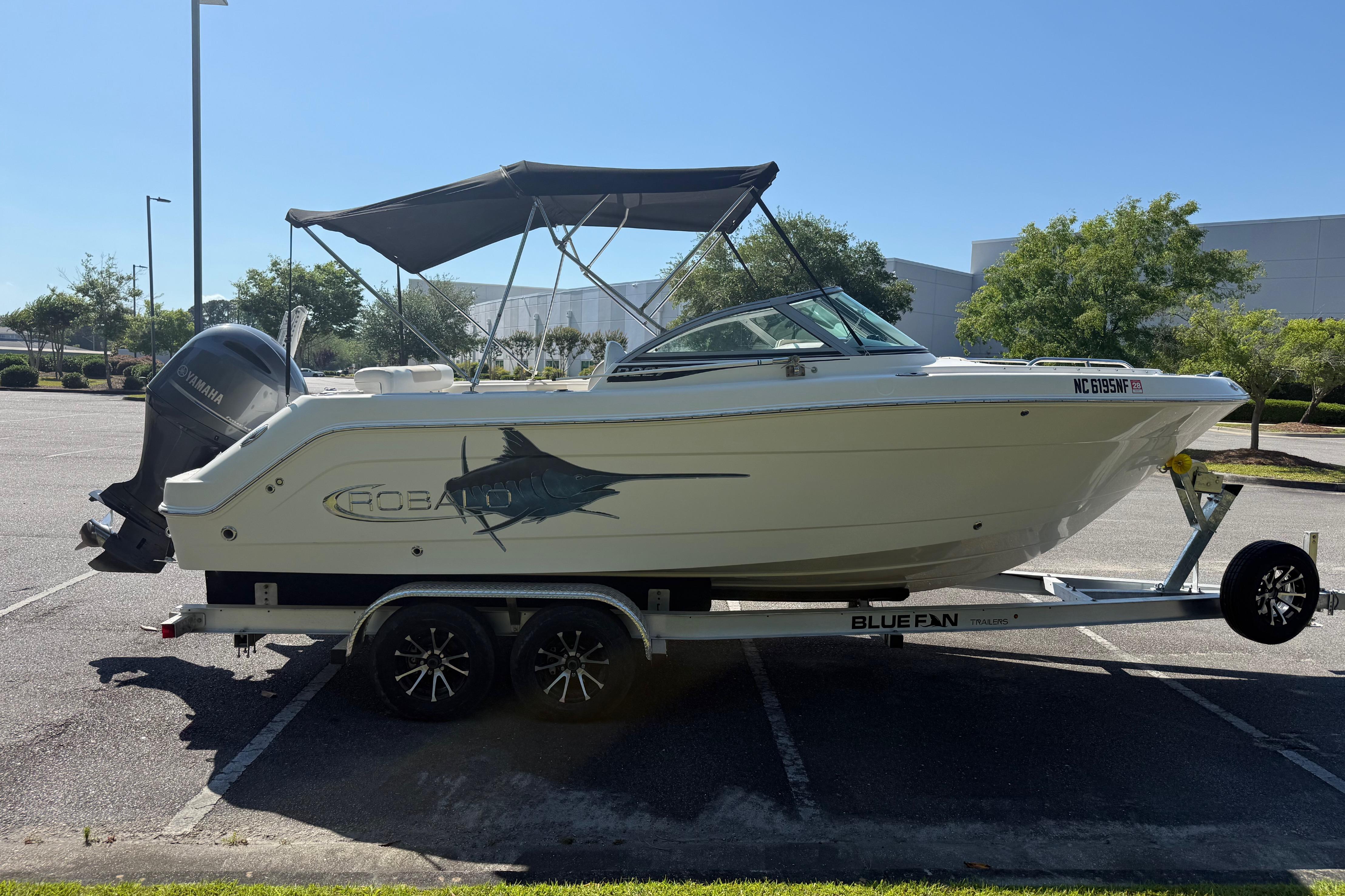 2015 Robalo R227 Dual Console boat on trailer in parking lot.