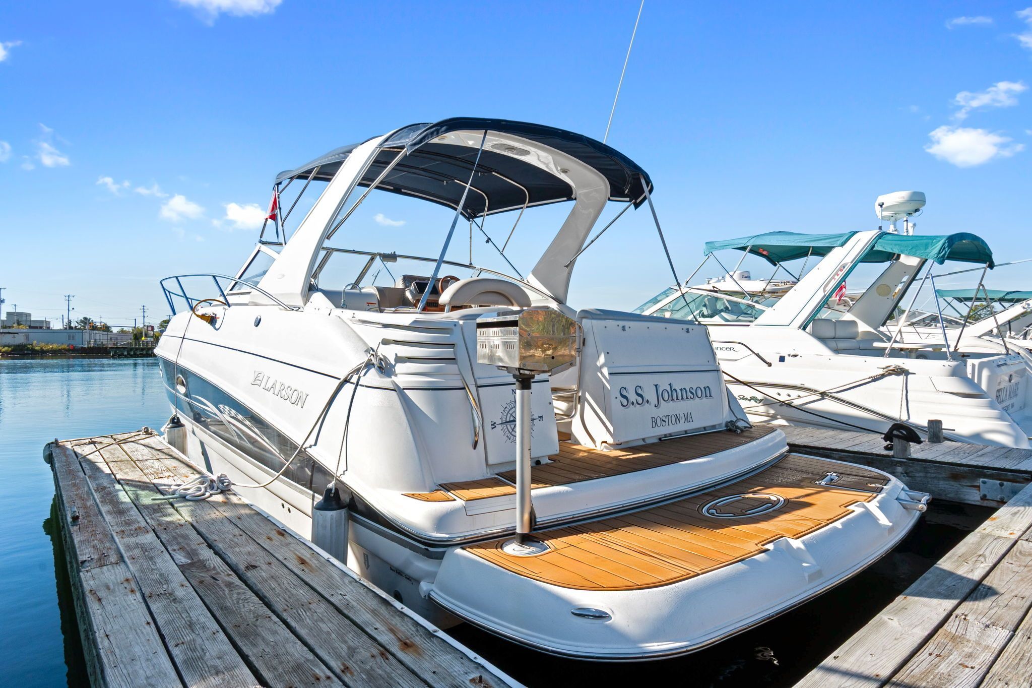 2007 Larson Cabrio 330 at dock with blue canopy and wooden deck.