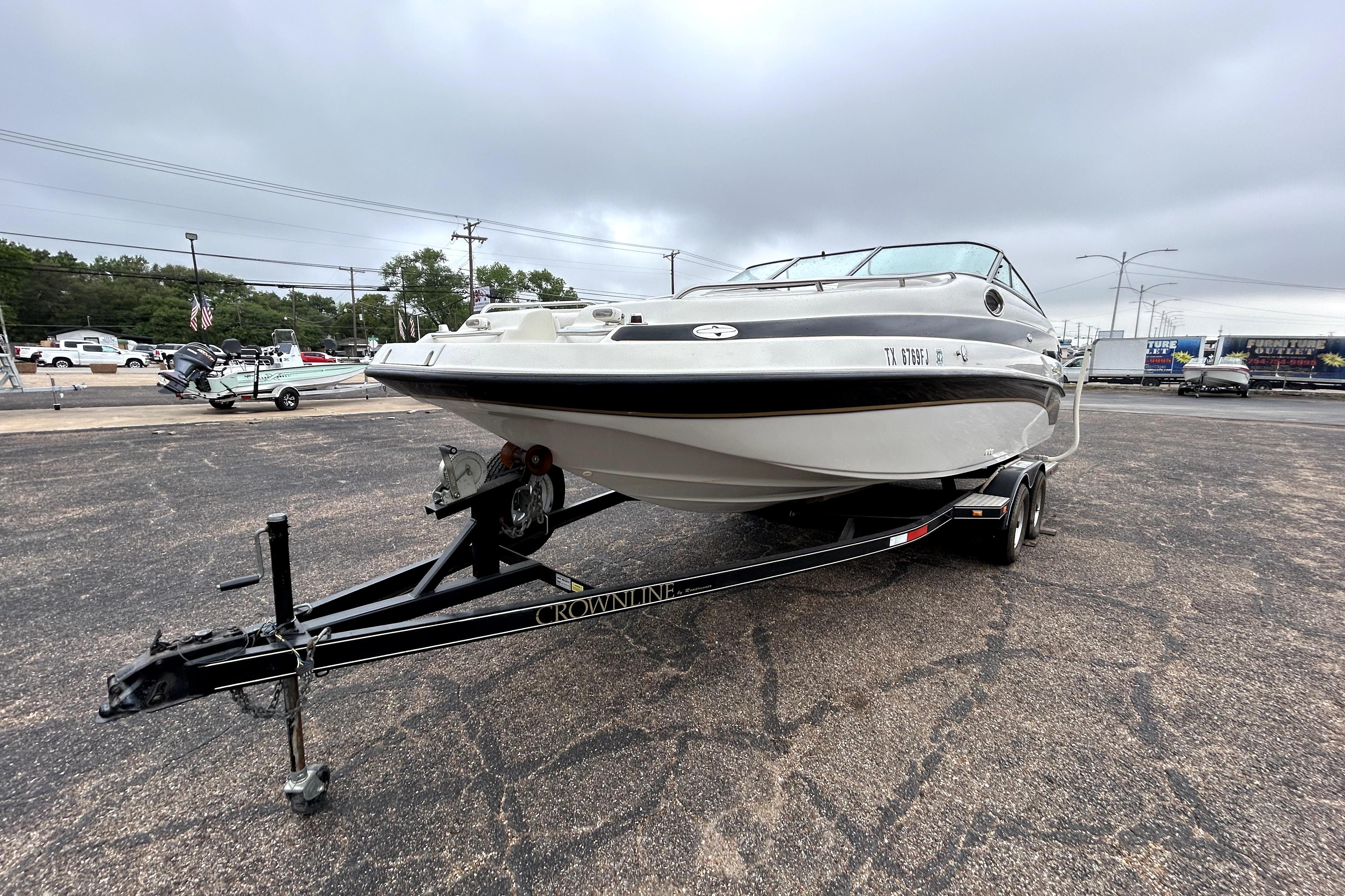 2001 Crownline 239 DB boat on trailer in parking lot, overcast sky.