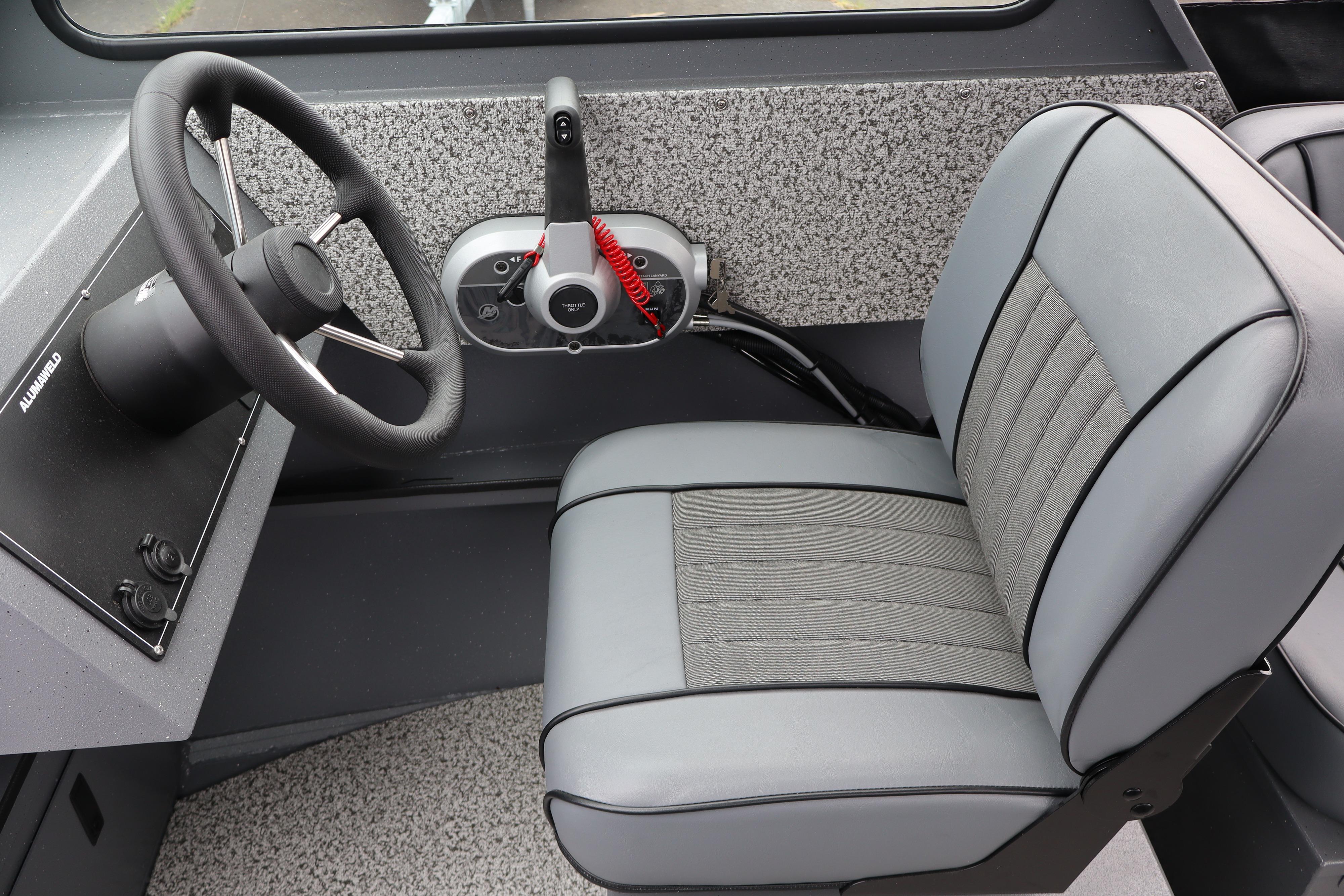 Interior of 2026 Alumaweld Stryker X202 boat, featuring steering wheel and cushioned seat.
