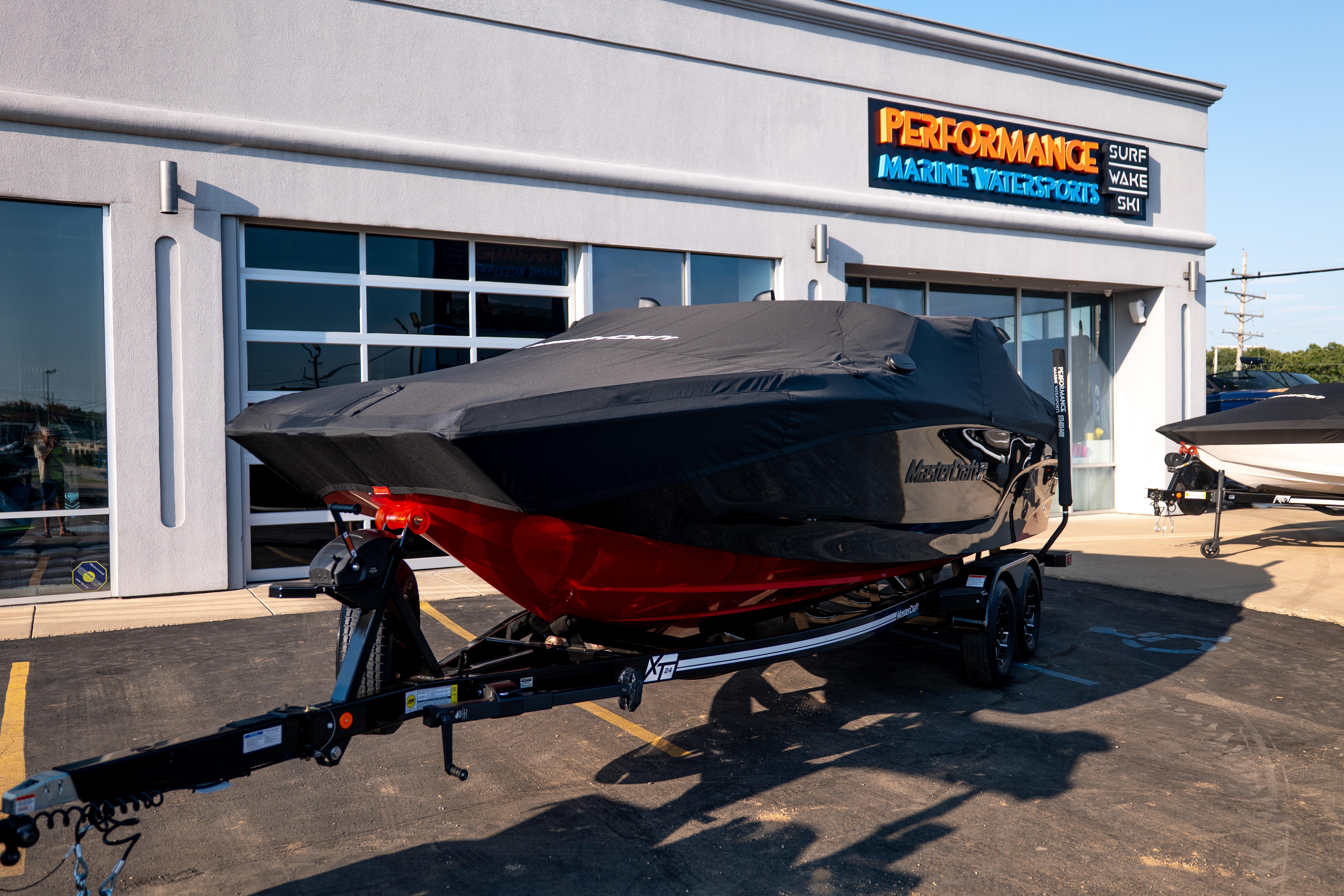2027 MasterCraft XT24 boat covered, parked outside Performance Marine Watersports dealership.