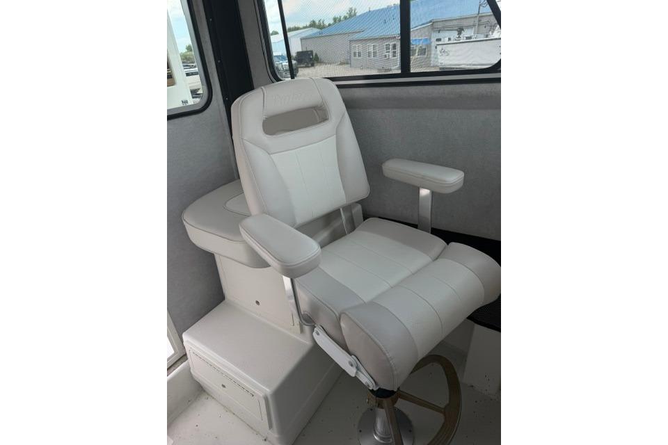 Captain's chair inside 2016 Parker 2520 Sport Cabin boat, featuring white upholstery and armrests.