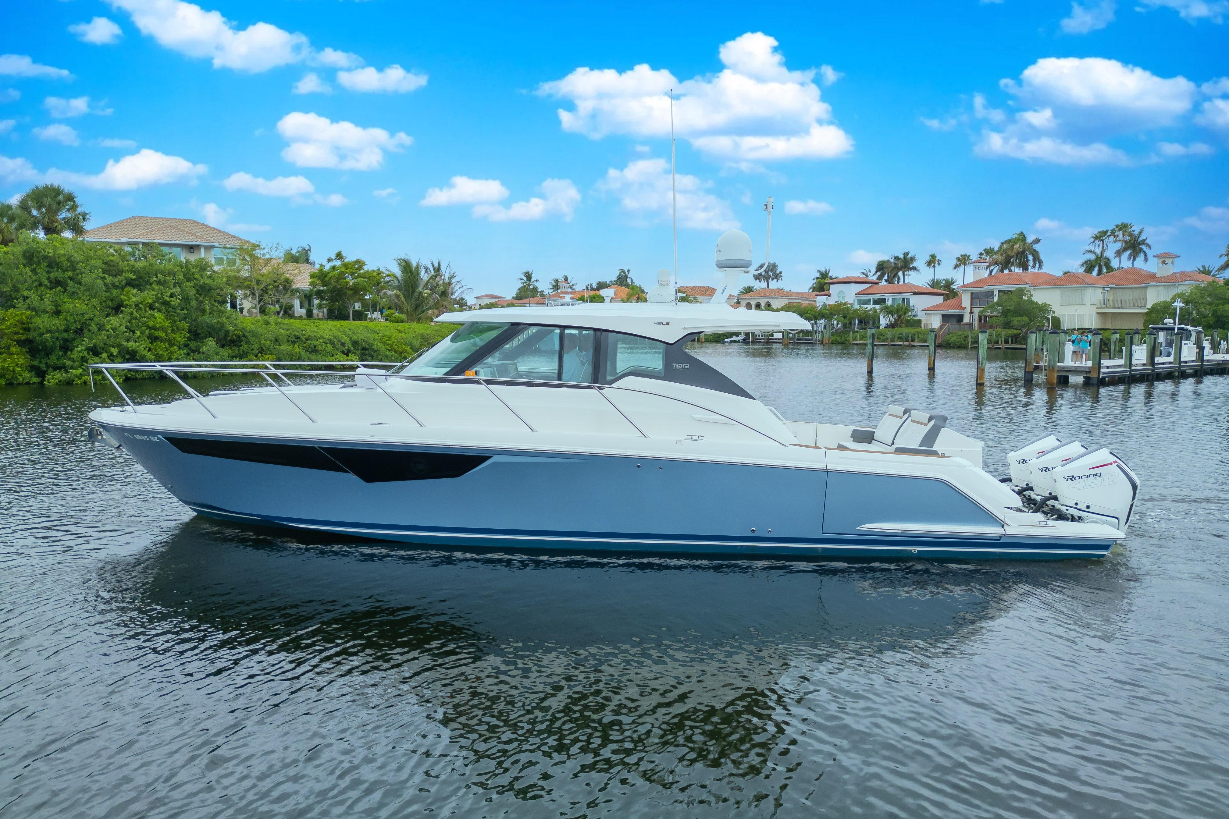 2021 Tiara Sport 43 LE luxury yacht on a serene waterway, under a clear blue sky.