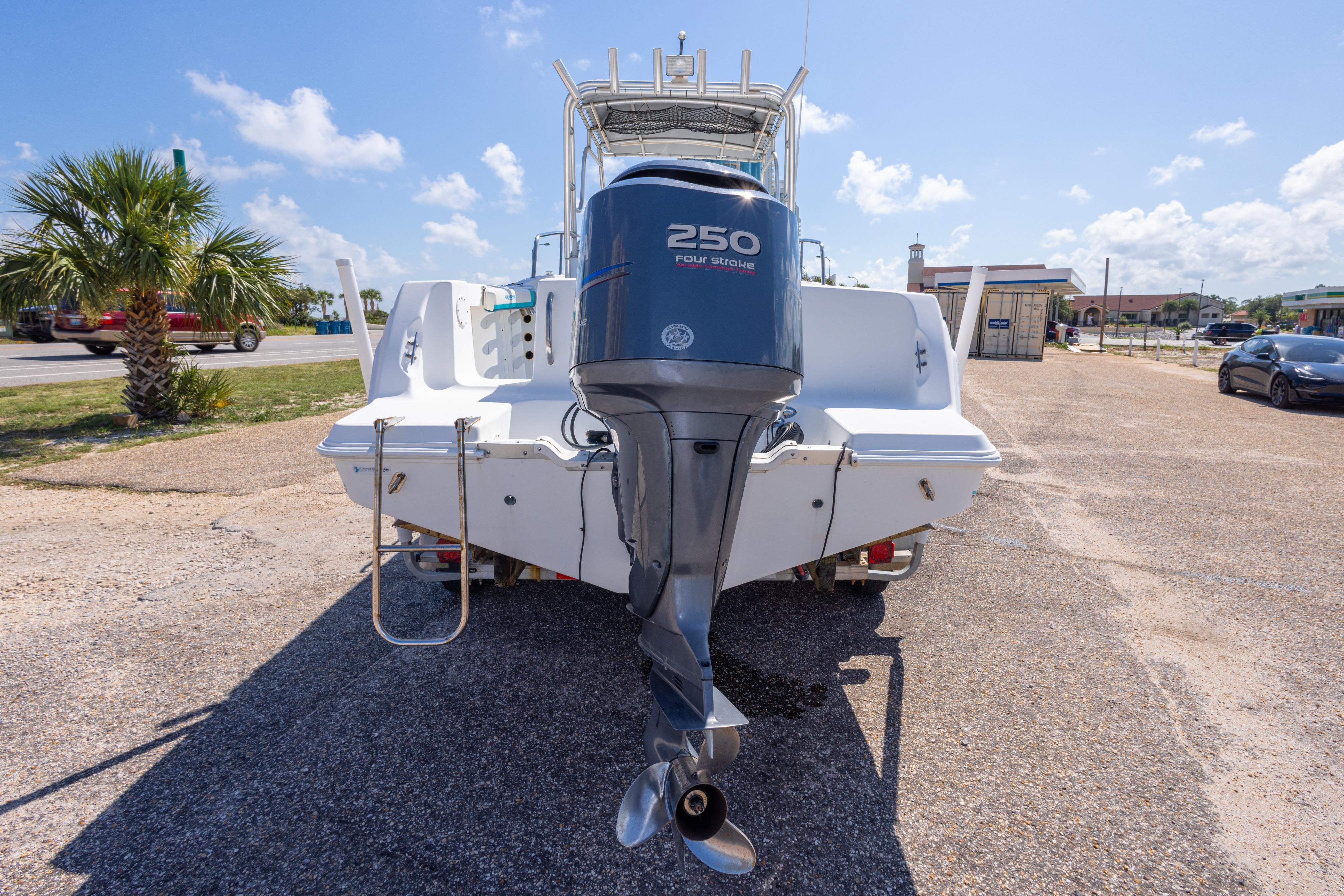 1999 Aquasport 225 Explorer boat with 250 horsepower engine, parked outdoors.