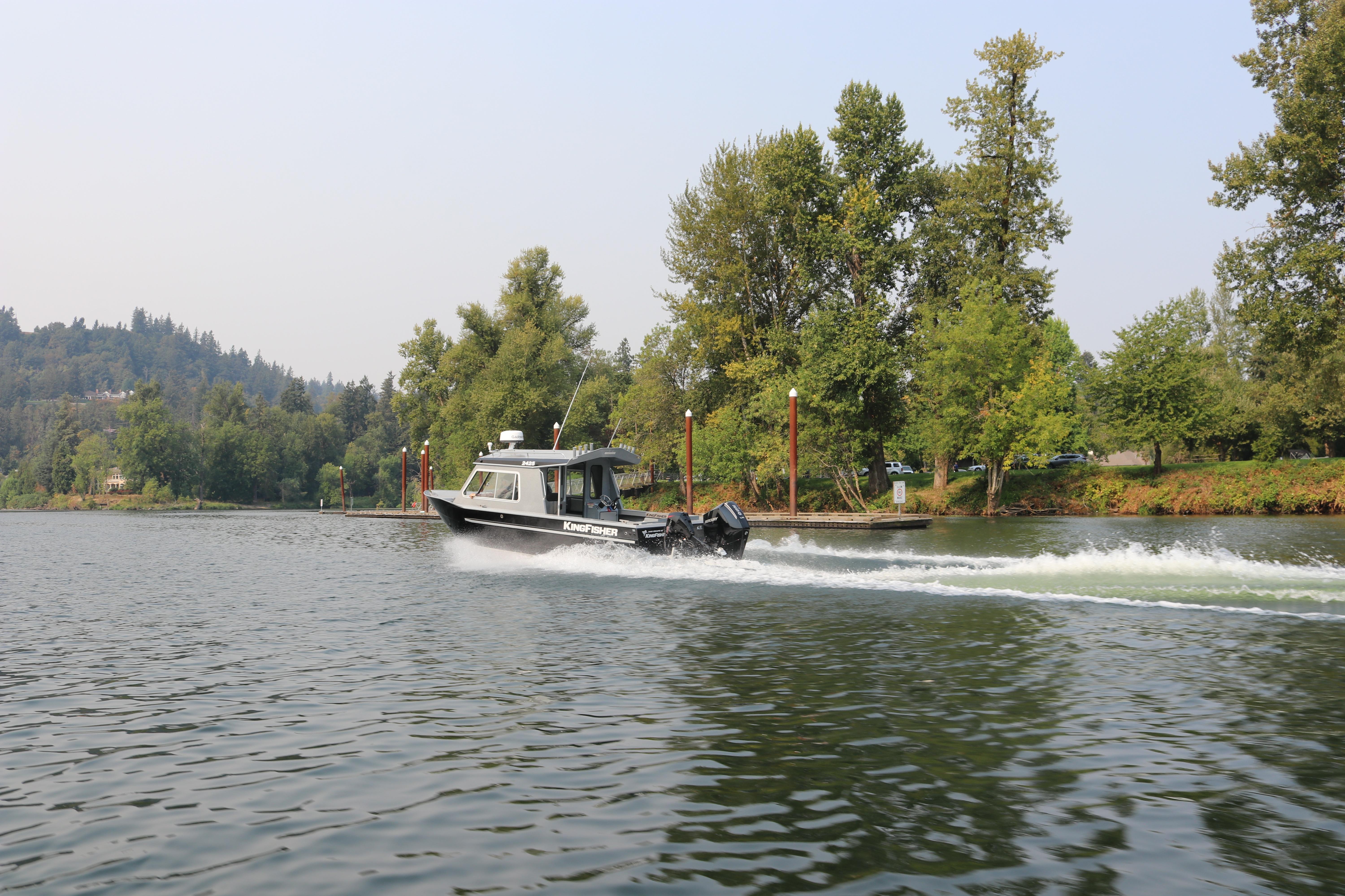 2026 KingFisher 2425 Escape HT cruising on a scenic river with lush greenery.