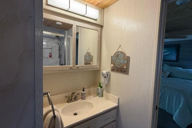 Bathroom interior of 1997 Stardust Houseboat 18x83, featuring a sink, mirror, and decor.
