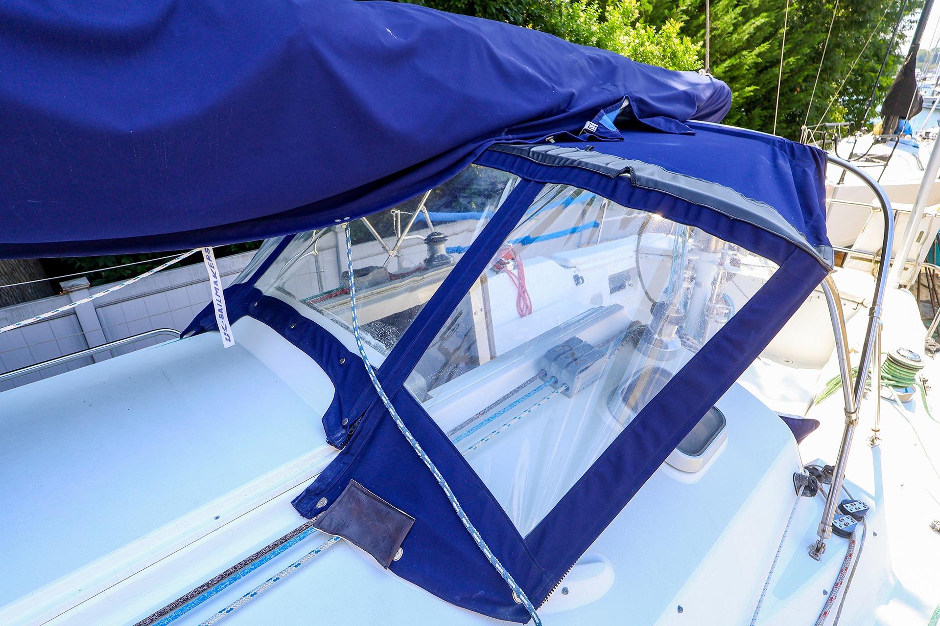 2001 J Boats J/32 sailboat with blue canvas cover and clear windows.