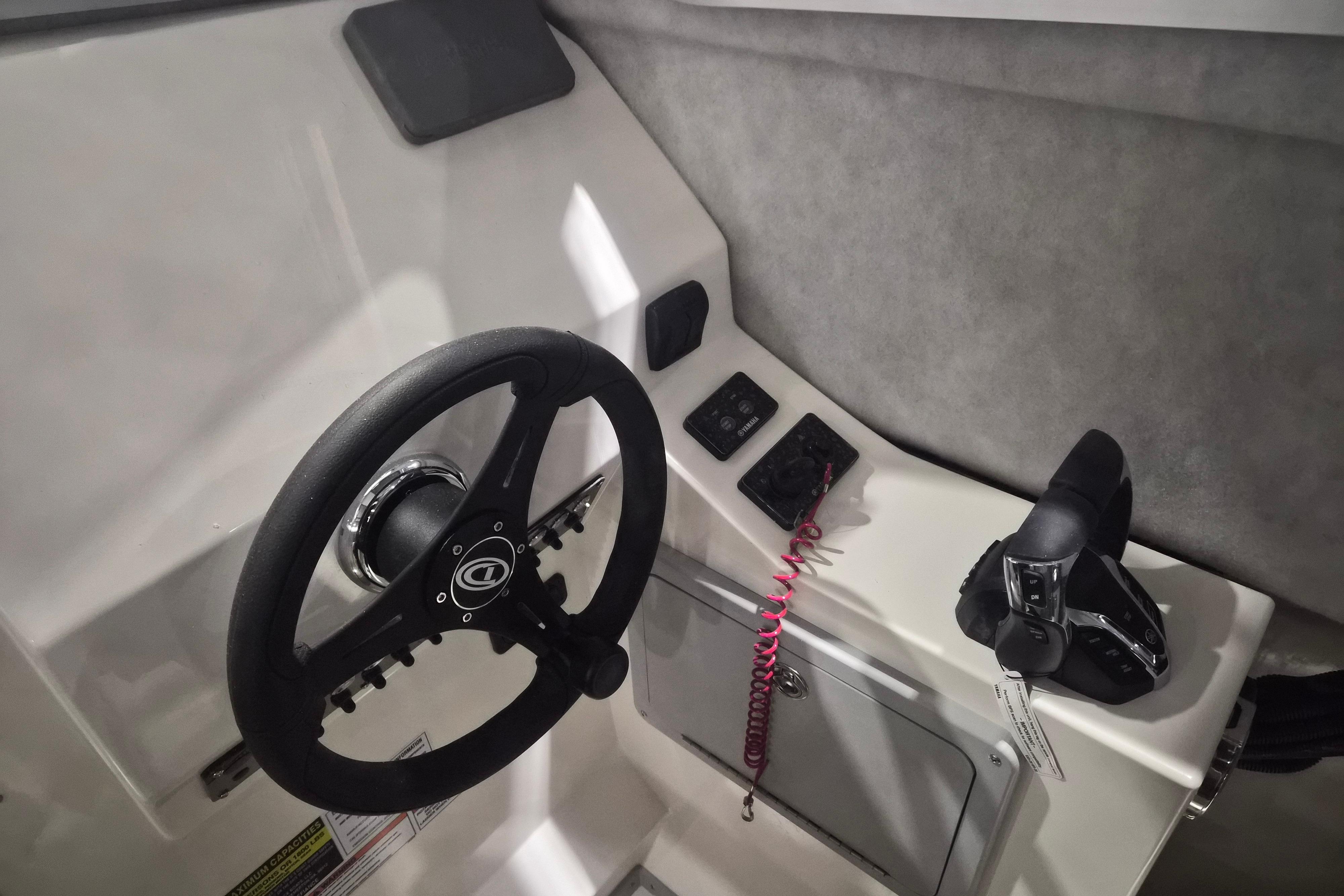 Steering console of 2026 Defiance Admiral 260 EX boat with controls and steering wheel.