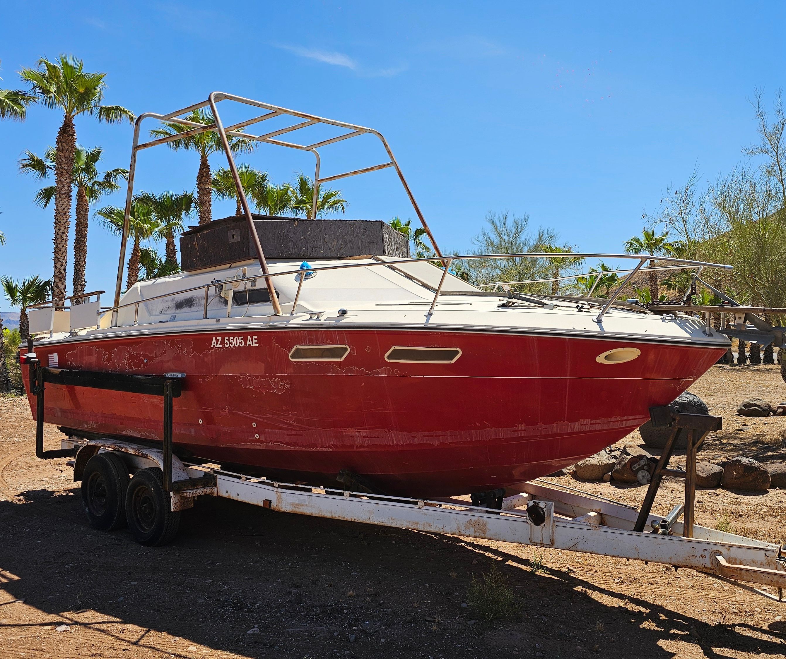 Red 1975 Sea Ray Cabin Cruiser on trailer outdoors.