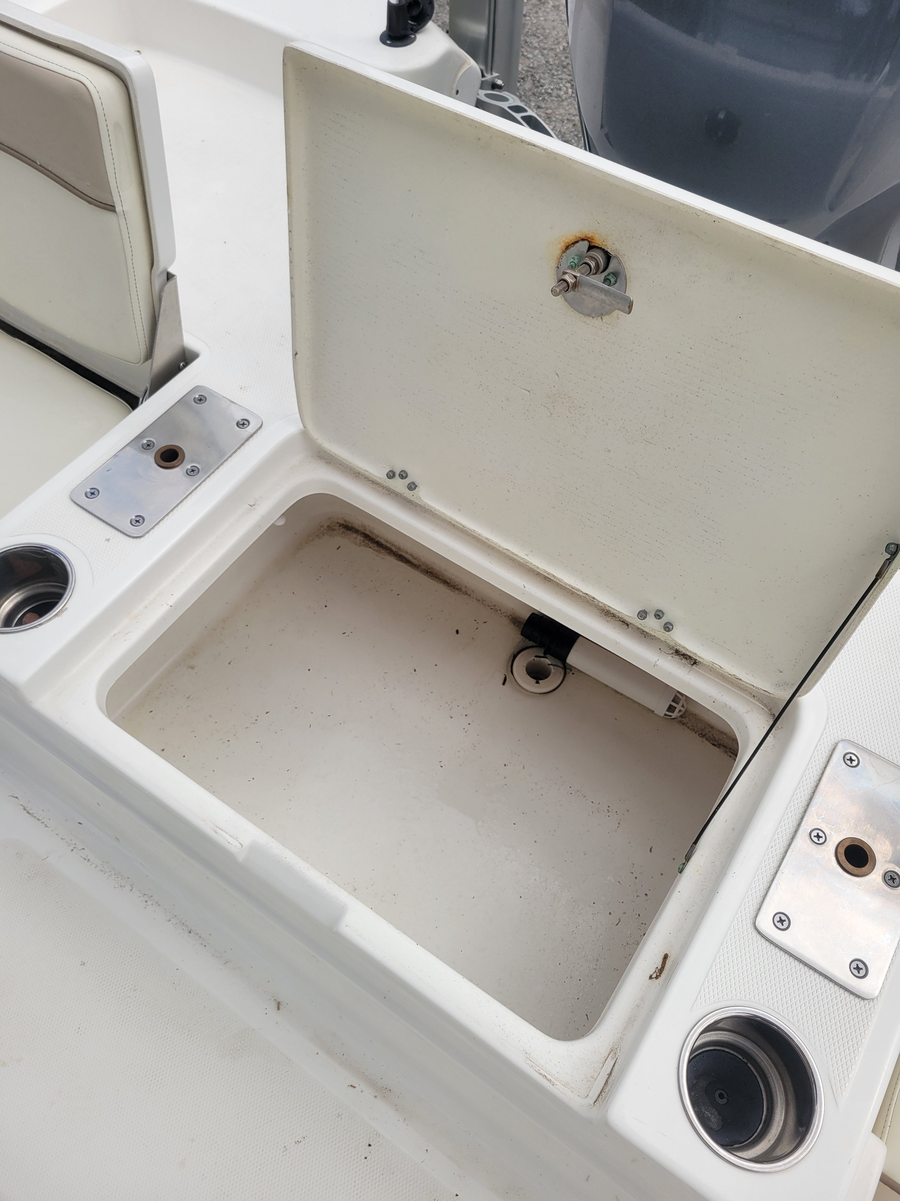 An open storage compartment on a boat with cup holders beside it.