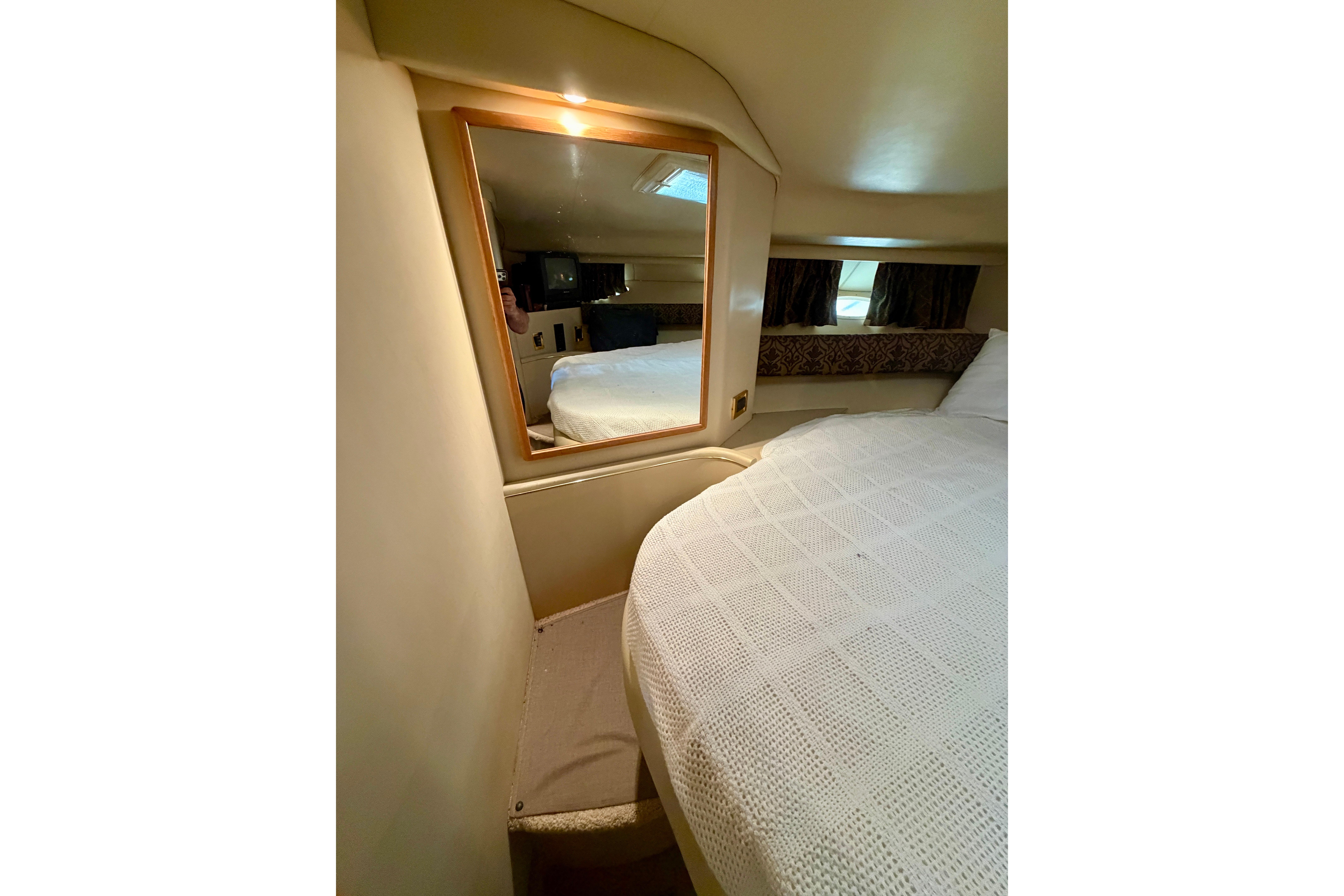 1999 Sea Ray 400 Sundancer cabin interior with bed, mirror, and window.
