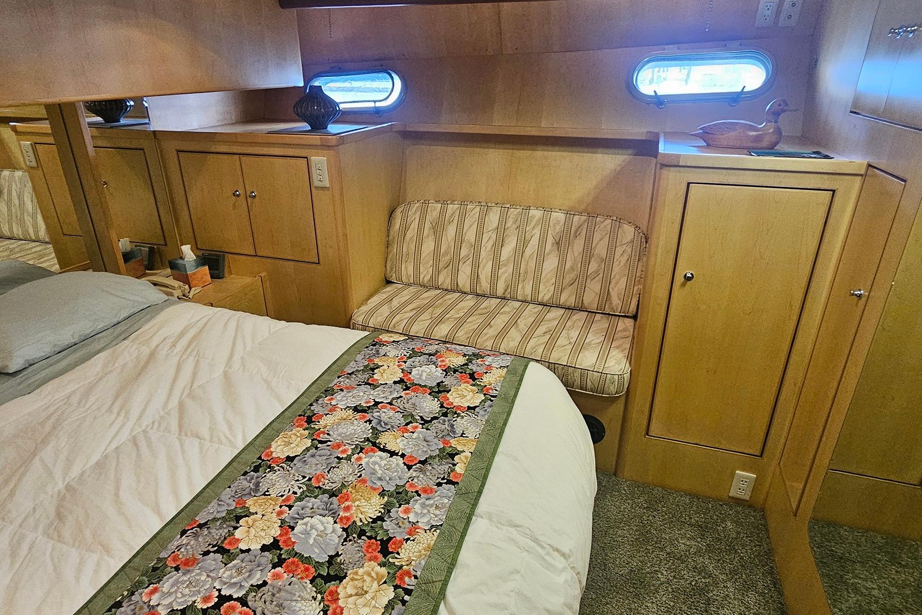 Cozy bedroom in 1995 Symbol 55 yacht with floral bedspread and wooden cabinetry.
