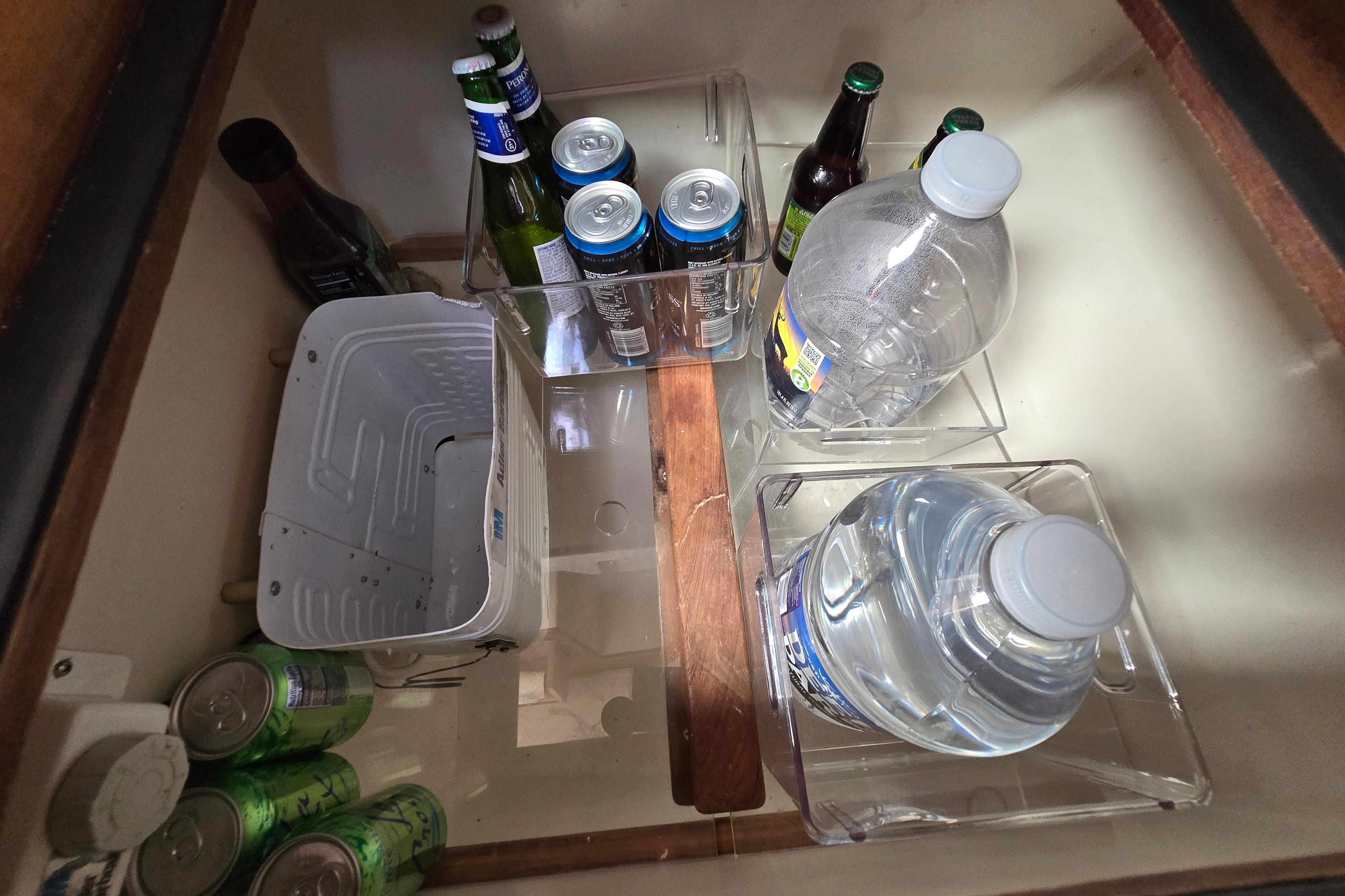Beverage storage in a 1993 Caliber 35 boat, featuring bottles and cans in a compartment.