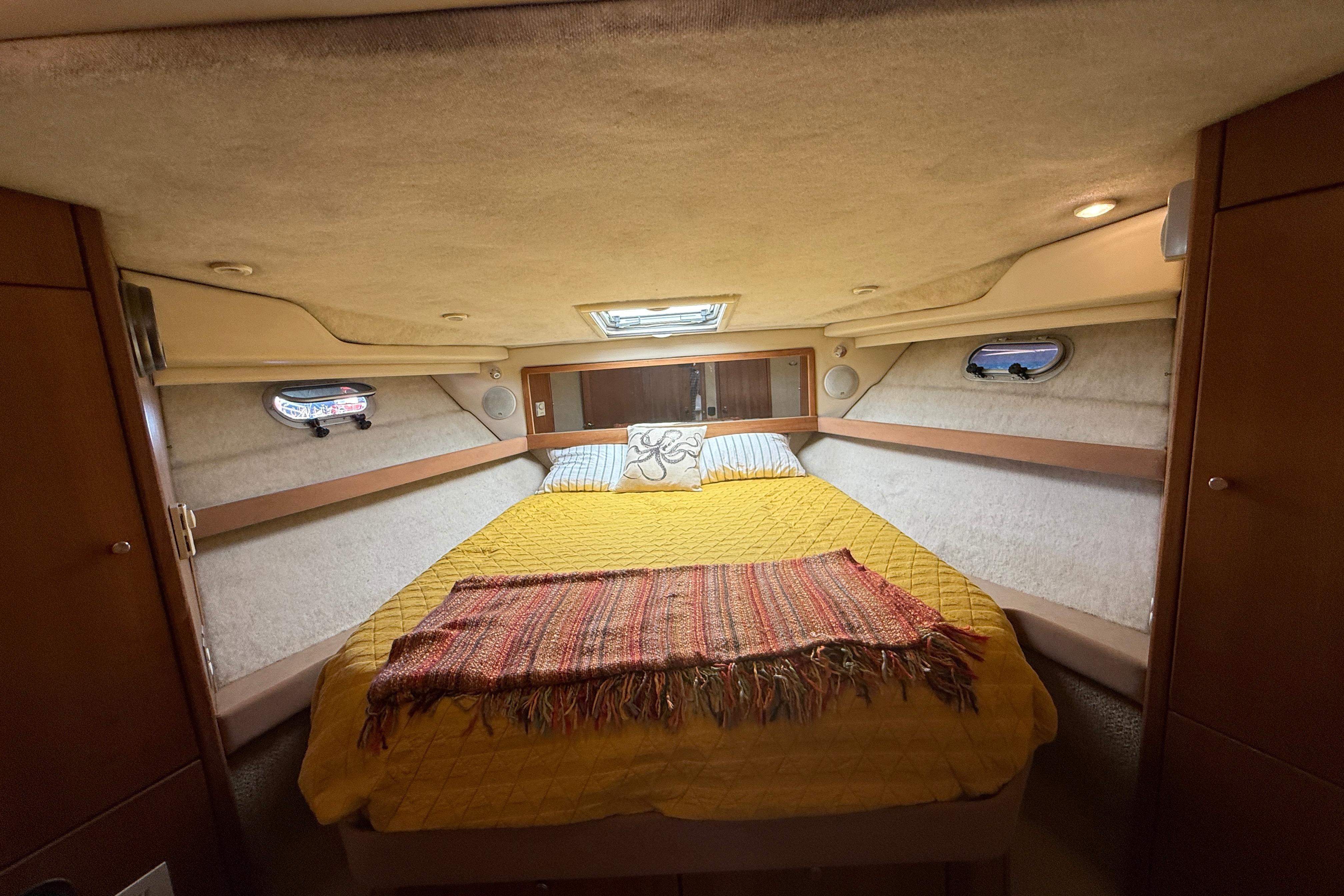 Cozy bedroom in 1997 Bayliner 3988 Command Bridge Motoryacht with yellow bedding and porthole windows.