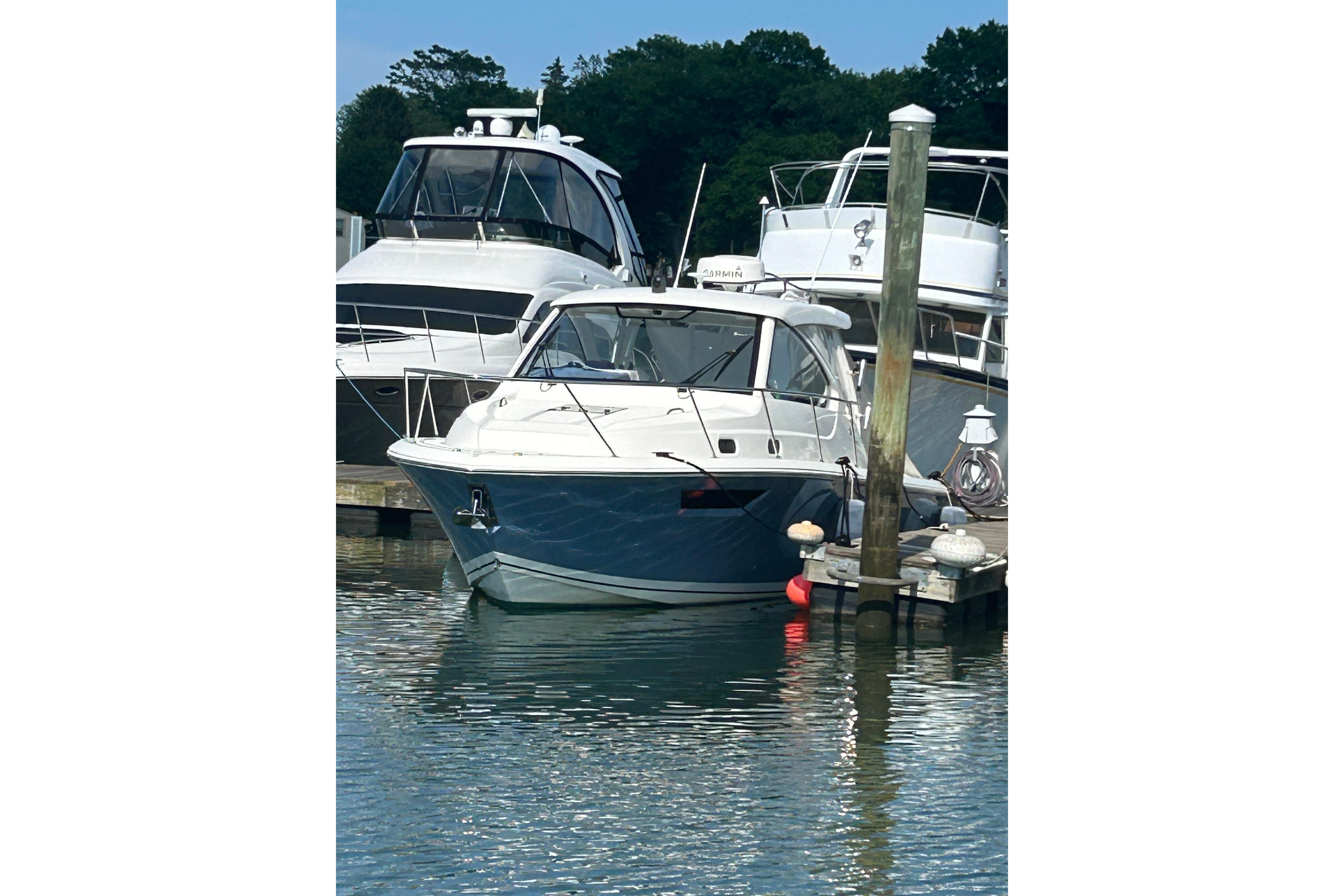 2021 Pursuit OS 325 Offshore boat docked at marina, surrounded by water and other vessels.