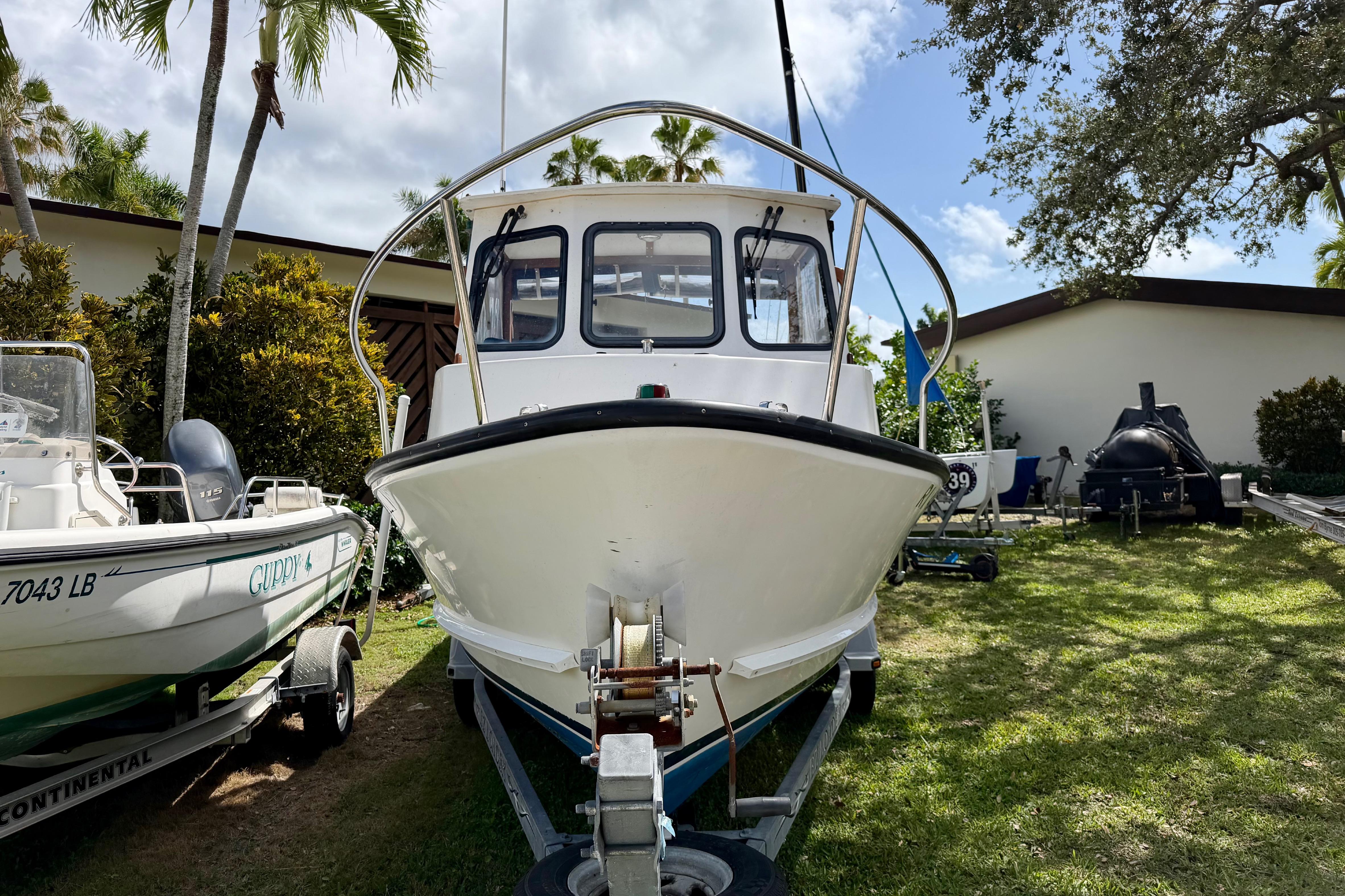 2000 Eastern 22 Lobster Fisherman boat on trailer, surrounded by palm trees and greenery.