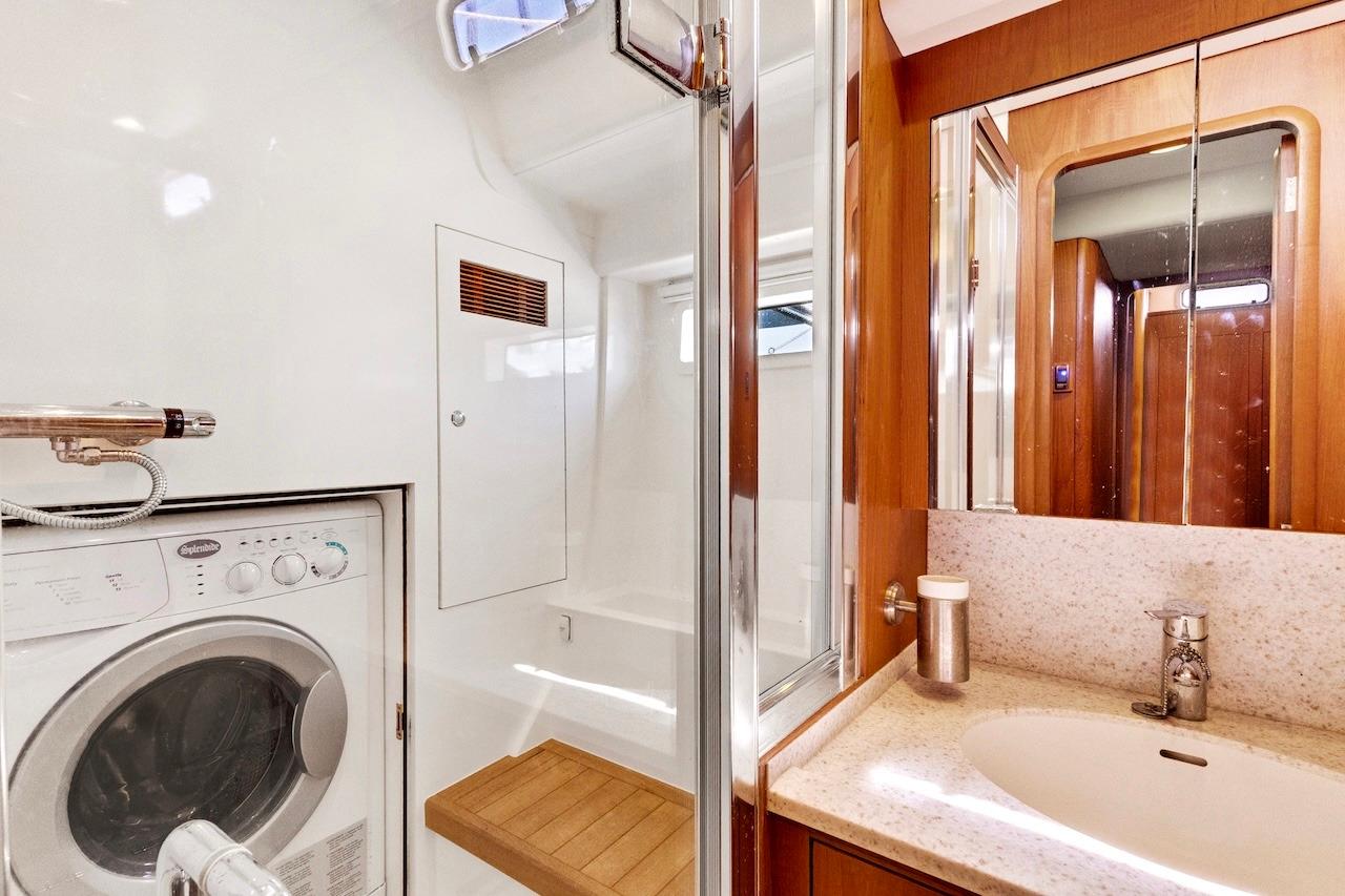 Laundry and bathroom area in 2011 Southerly 57 RS yacht, featuring washer and modern fixtures.