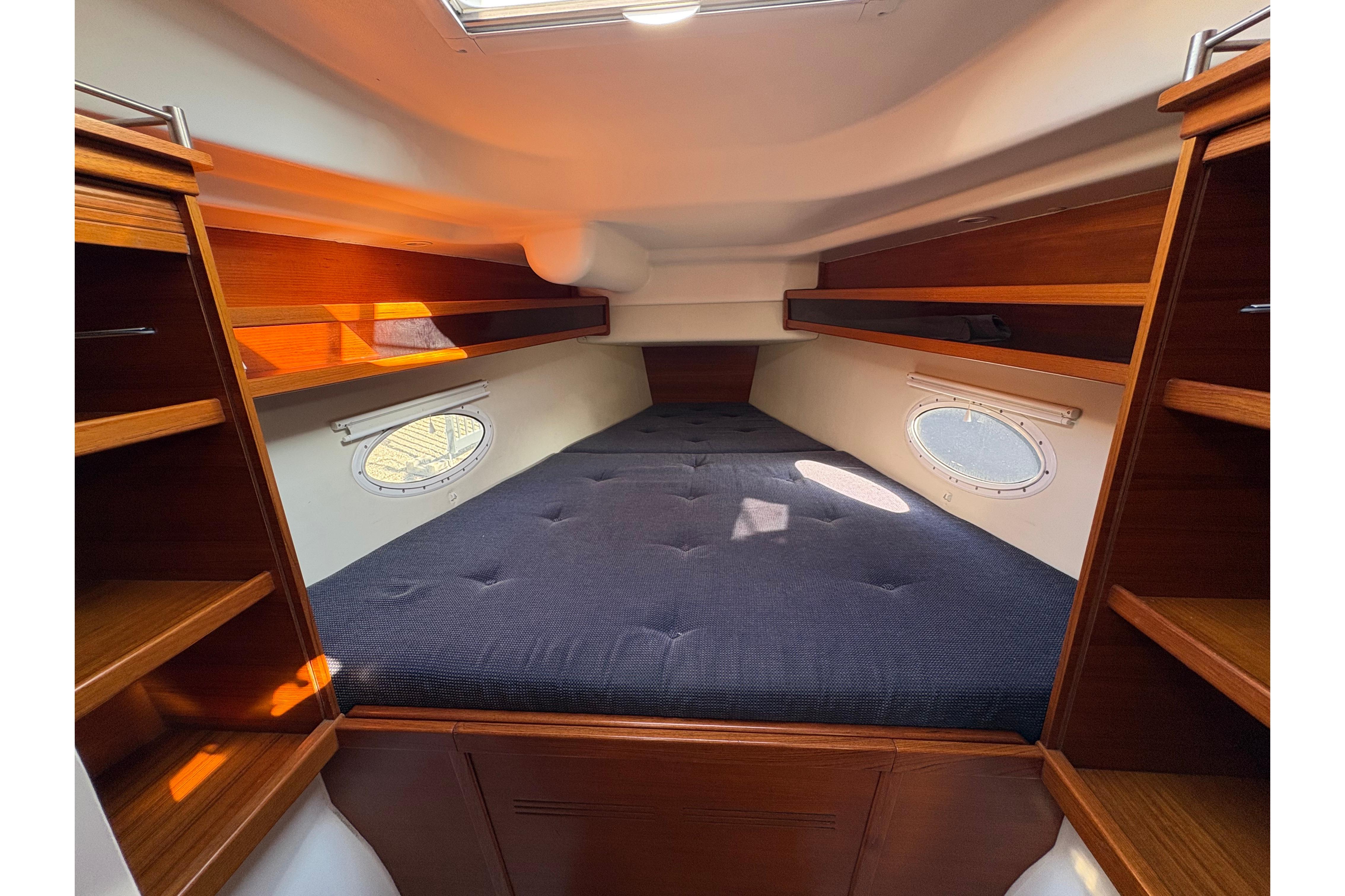 Cozy cabin interior of 2007 Dragonfly 35 sailboat with wooden shelves and portholes.