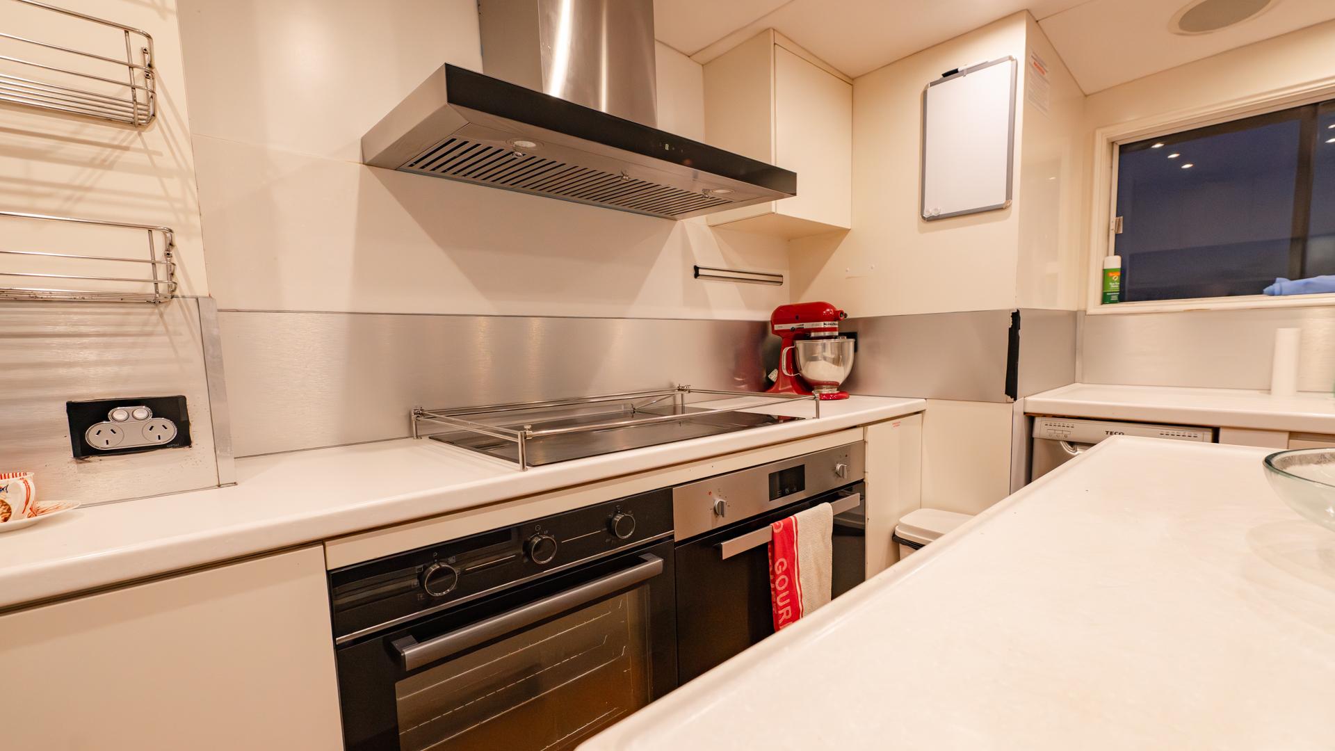 Modern yacht kitchen with stainless steel appliances, sleek countertops, and a mixer on the counter.