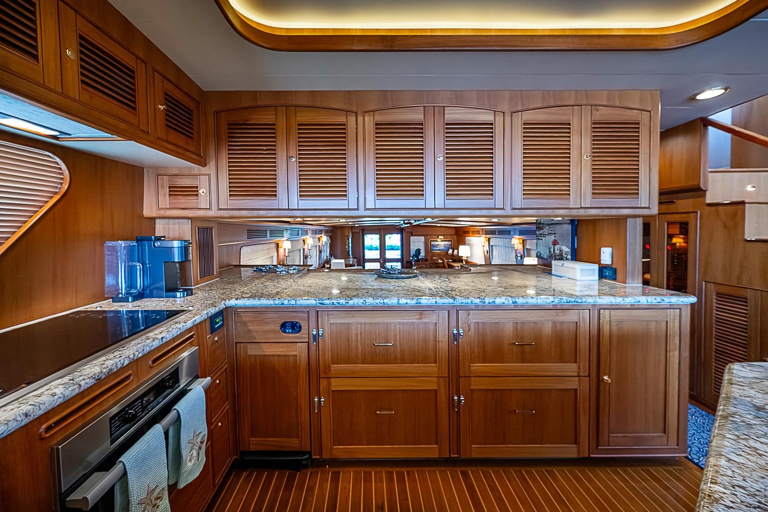 Luxurious kitchen interior of 2014 Marlow 80 Explorer yacht with wooden cabinetry and granite countertops.