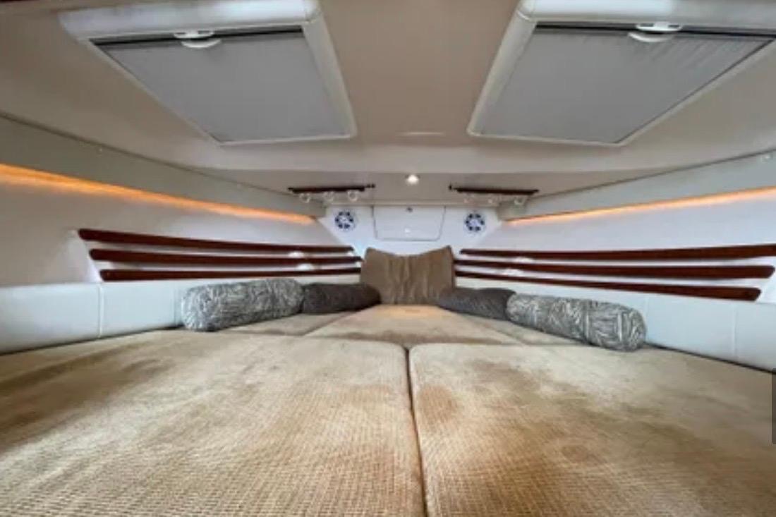 2007 Grady-White Express 330 cabin interior with cozy bedding and ambient lighting.