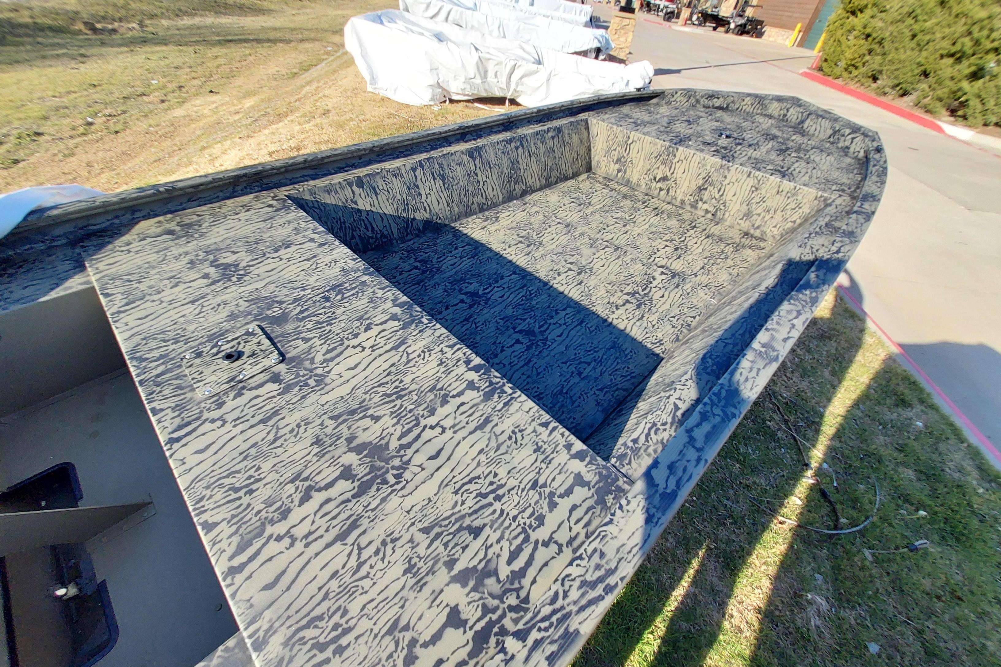 2026 Tracker Grizzly 1648 Utility boat with camouflage pattern, parked outdoors.